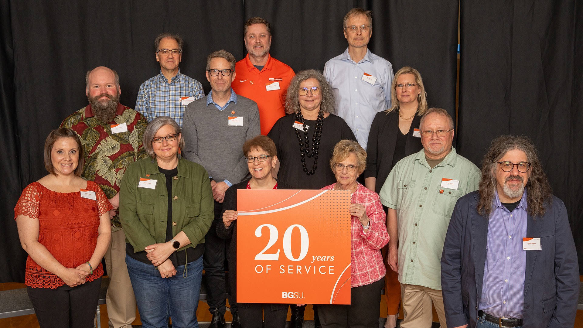 A group of people stands with a 20-year work anniversary sign