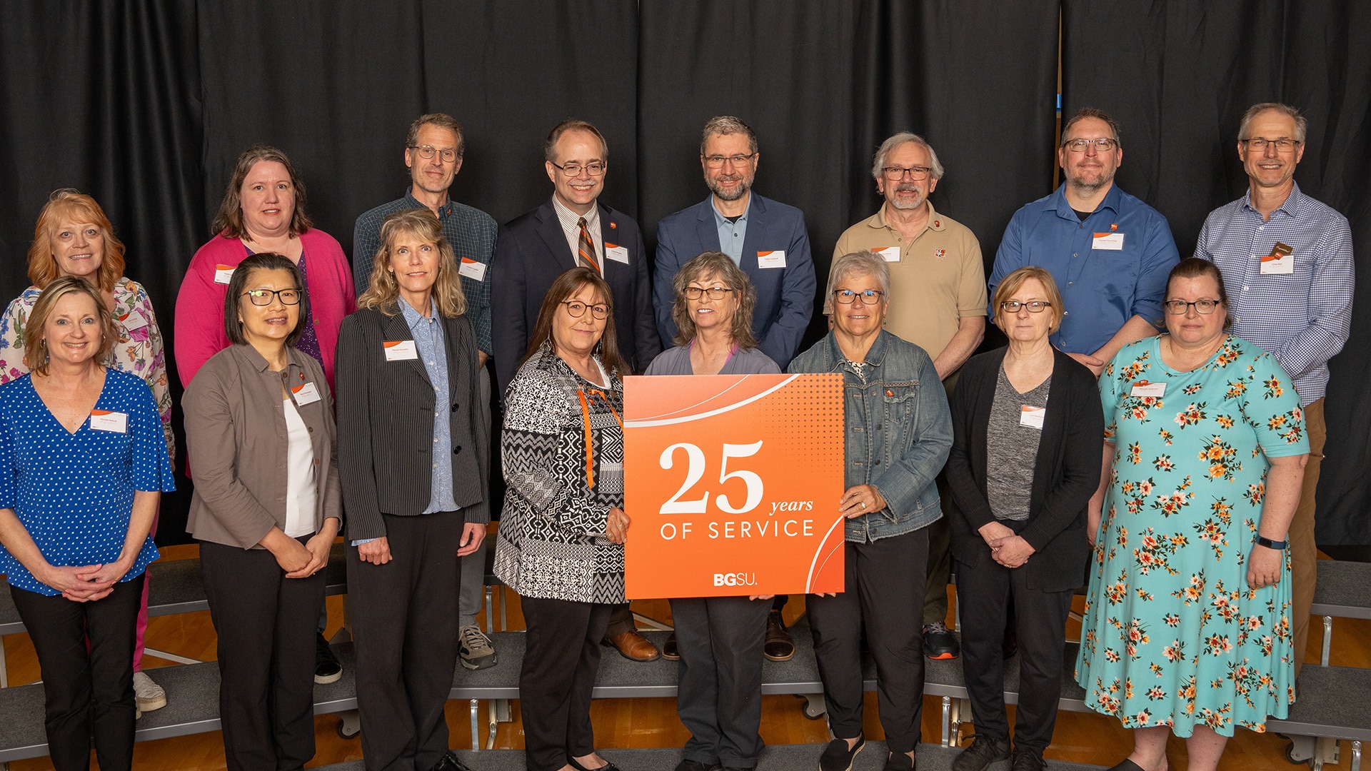 A group of people stands with a 25-year work anniversary sign