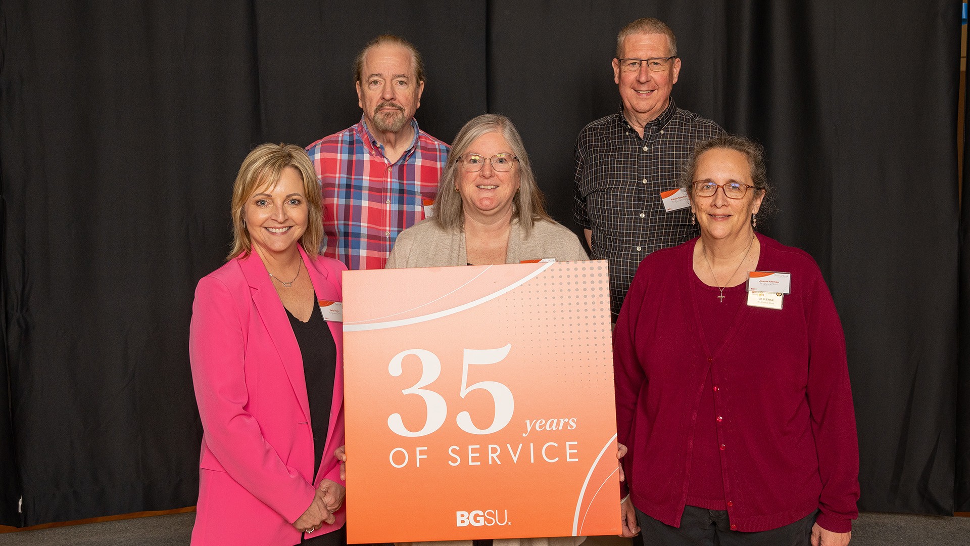A group of people stands with a 35-year work anniversary sign