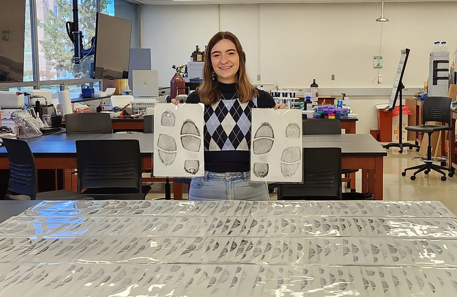 A student holds up shoe impressions.