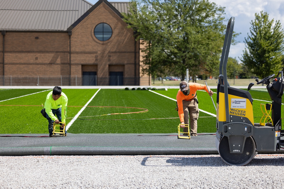 Workers install artificial turf