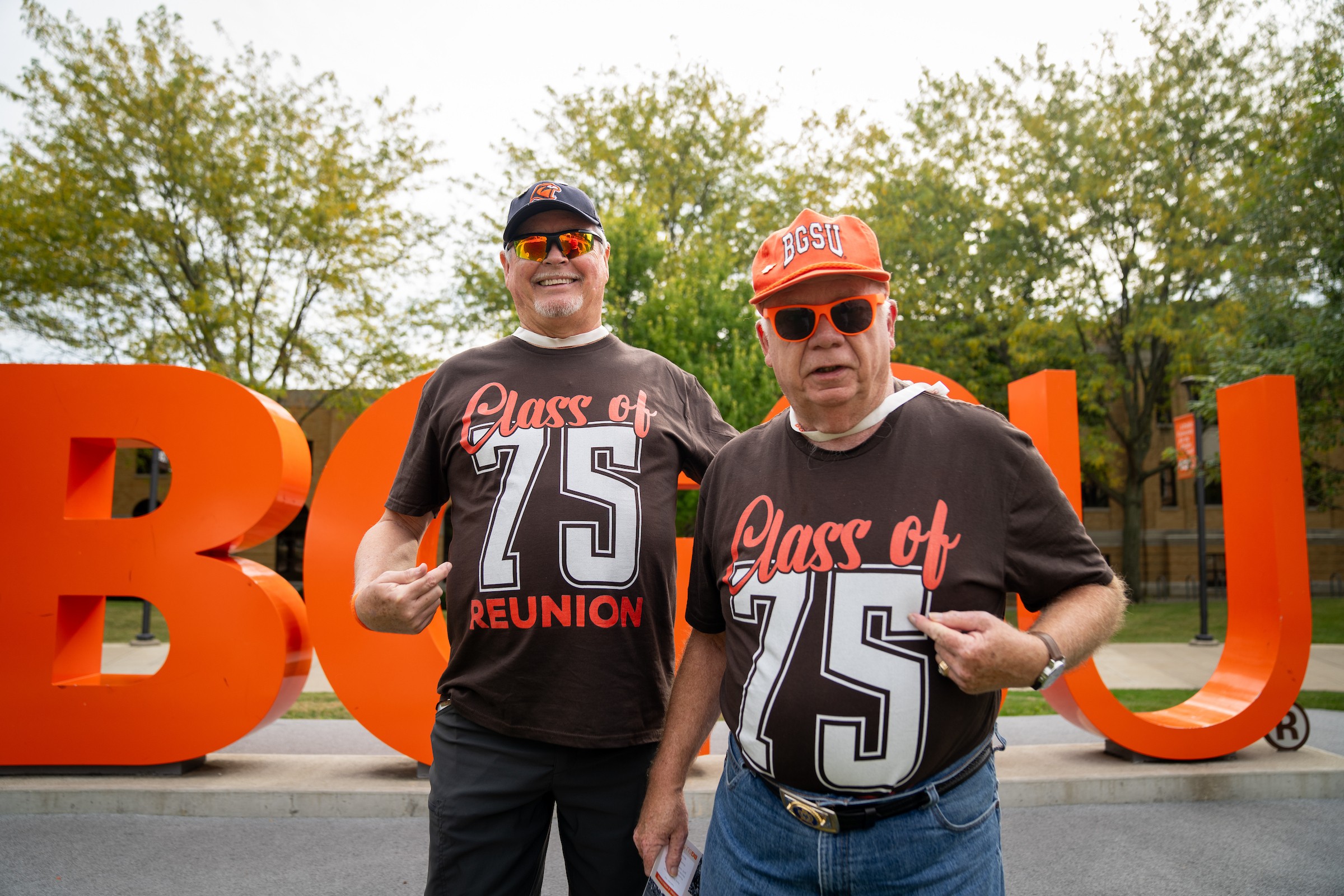 Two people wearing "Class of '75 Reunion" t-shirts pose for a photo