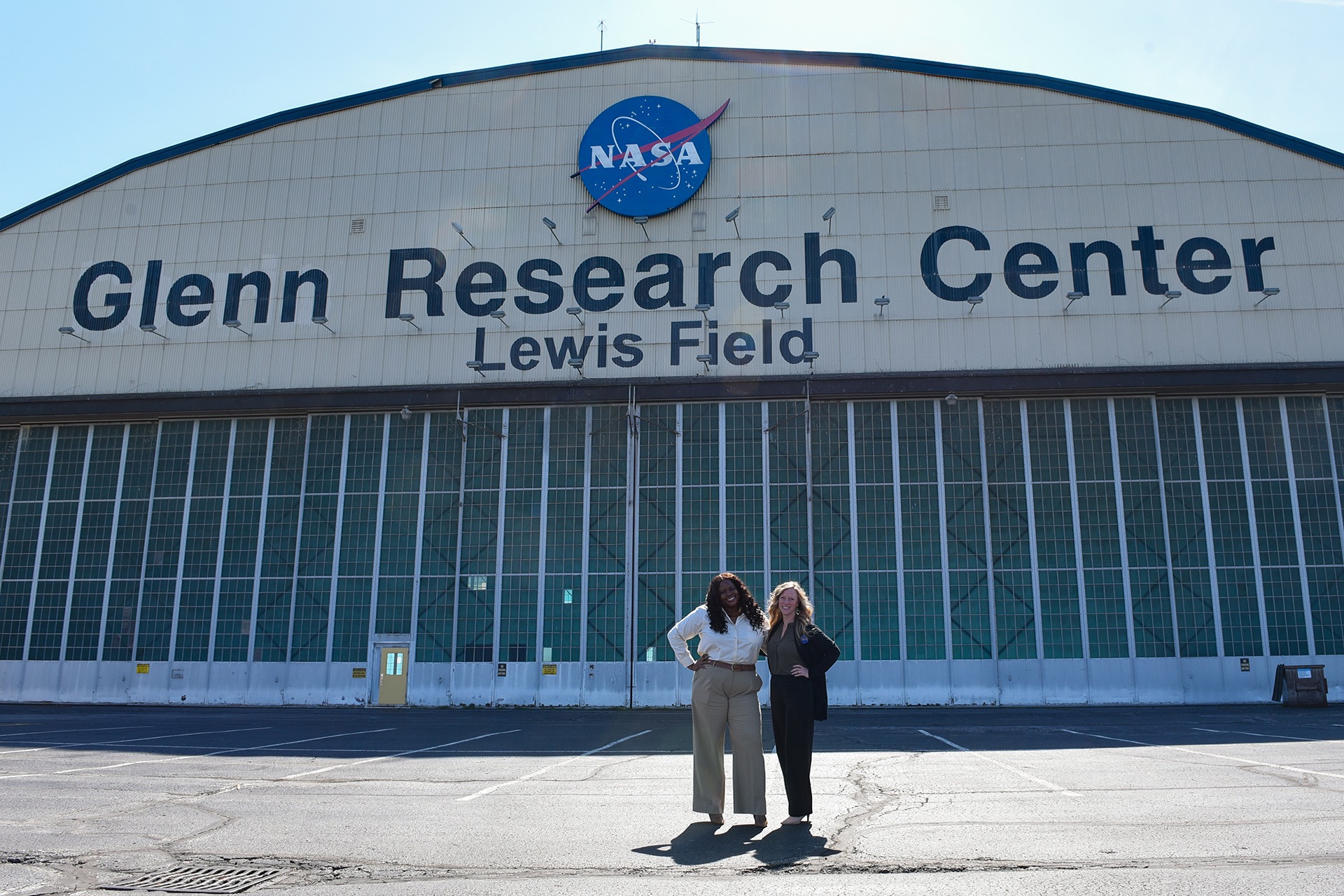 Two people pose in front of a building at the NASA Glenn Research Center.