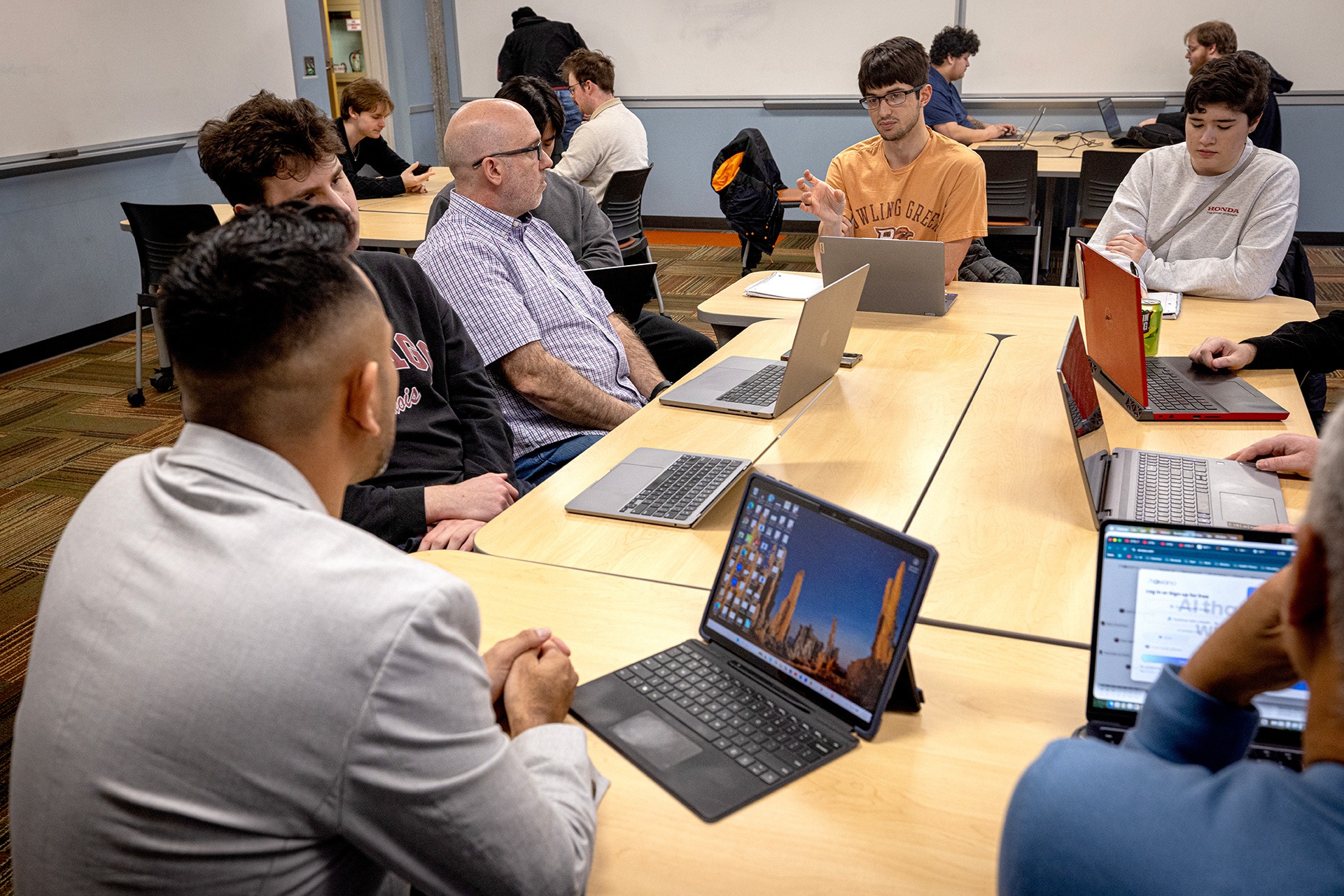 People with laptops sit at a group of desks