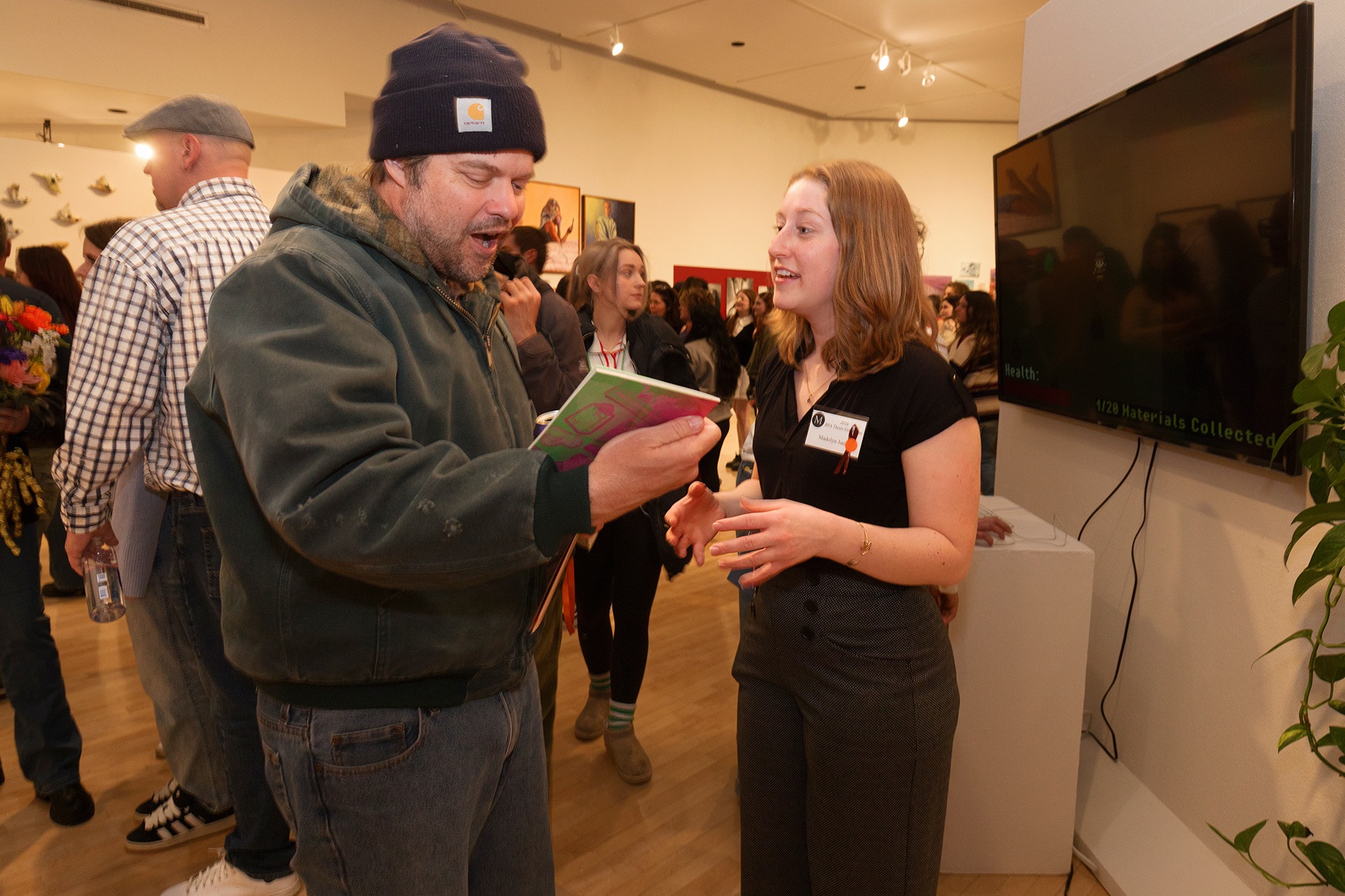A person looks excitedly at a booklet during an art exhibit