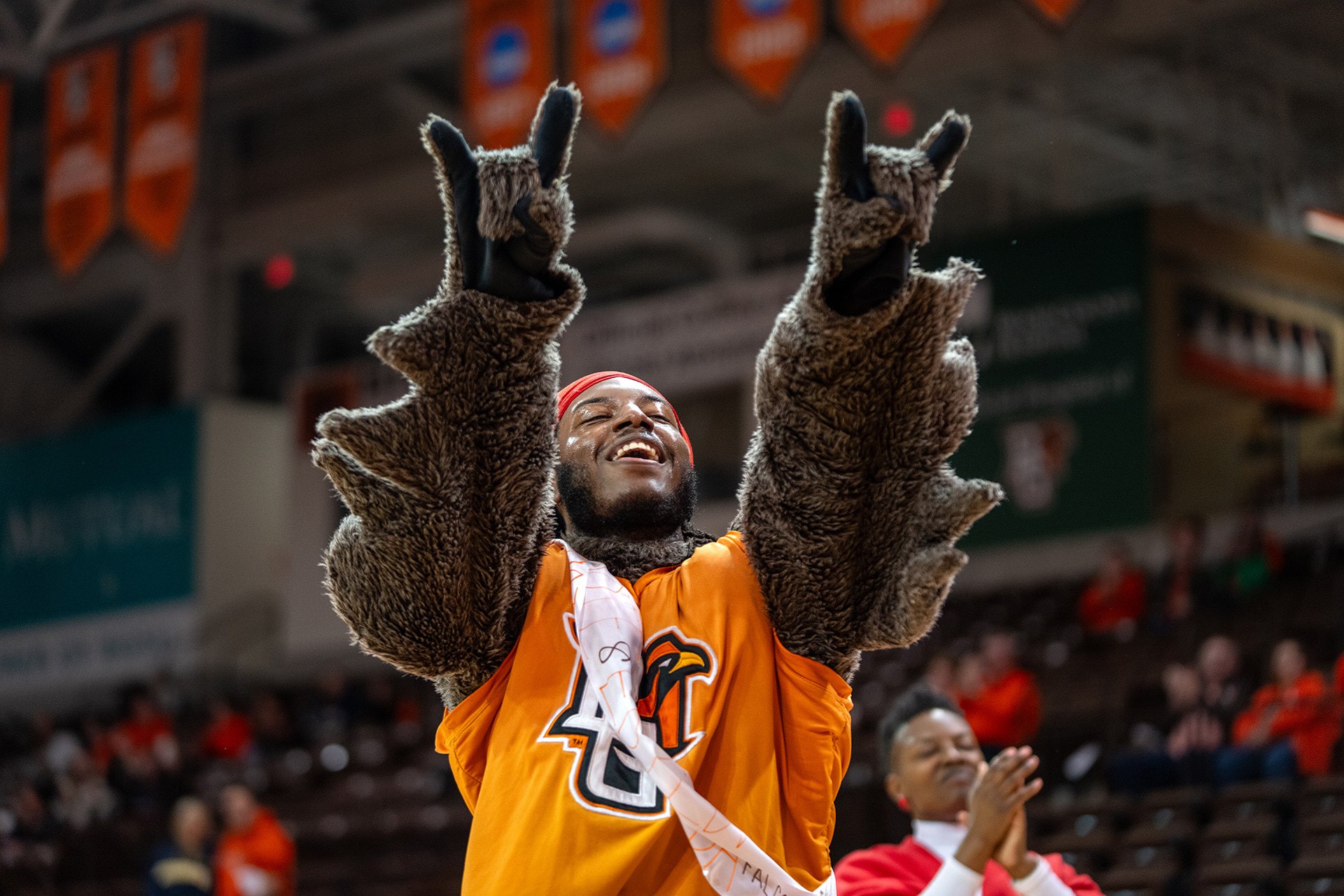 A person in a mascot costume lifts his hands in the air.