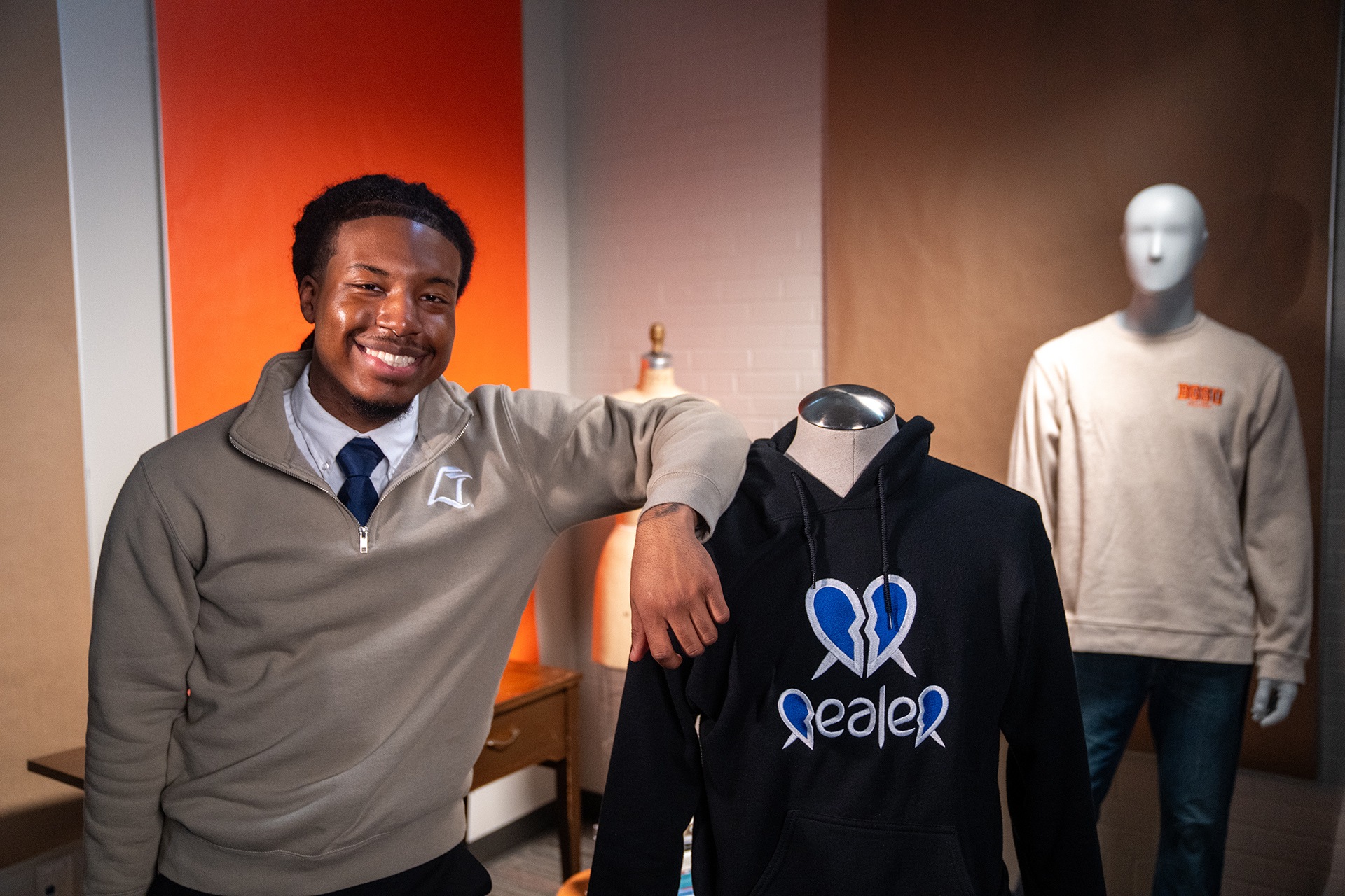 A person poses for a picture next to a mannequin wearing a hoodie.