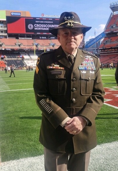 A military officer poses for a photo at a football game.