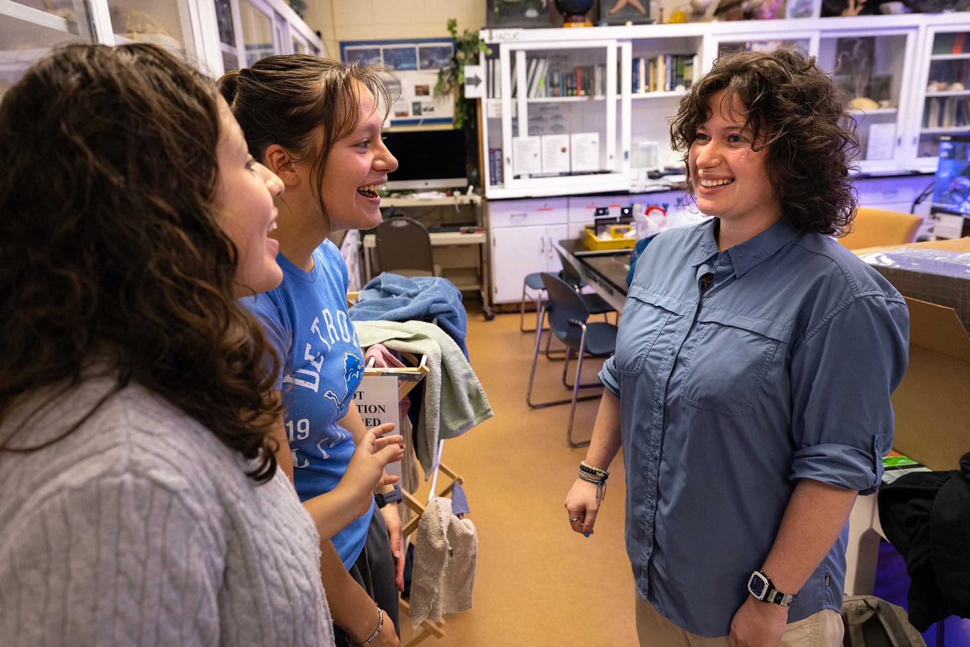 Three people smile while chatting together.