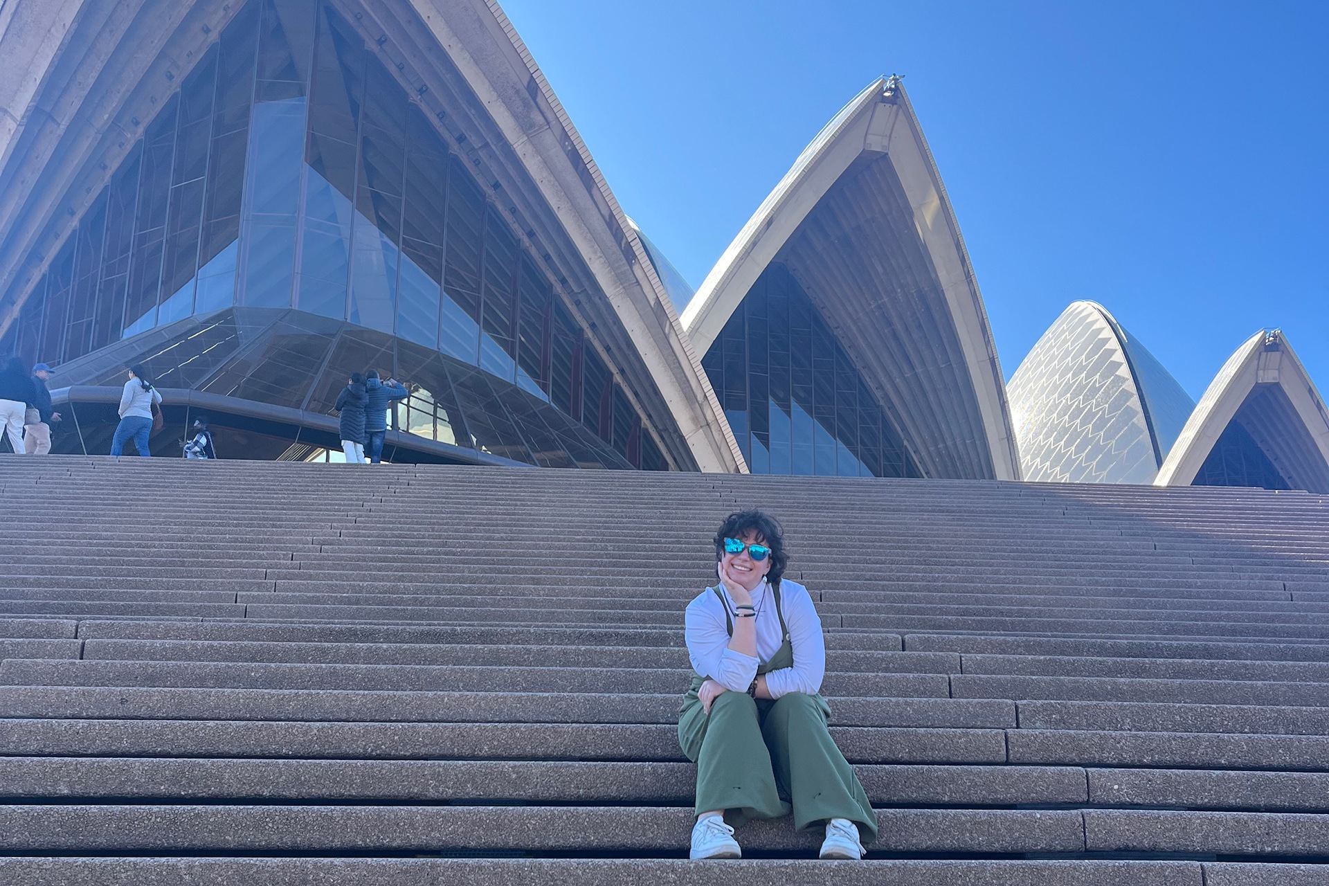 A person poses for a photo at the Sydney Opera House. 