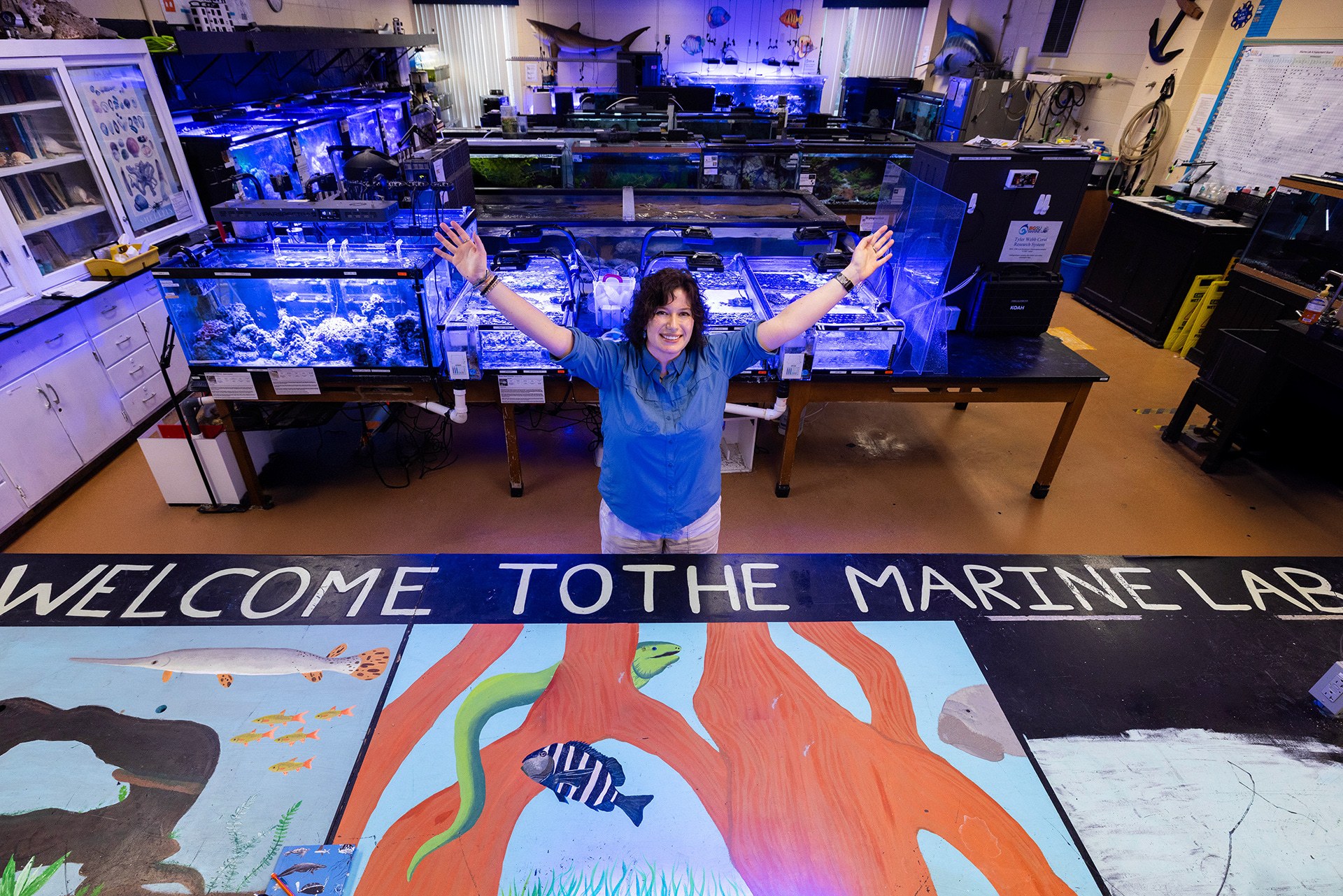 A person celebrates inside a laboratory with fish tanks.