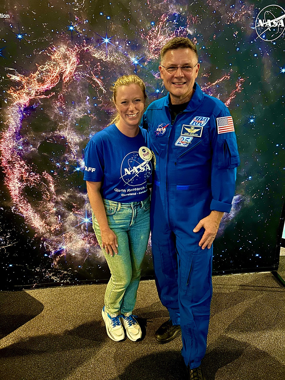A public affairs officer poses for a photo with an astronaut.
