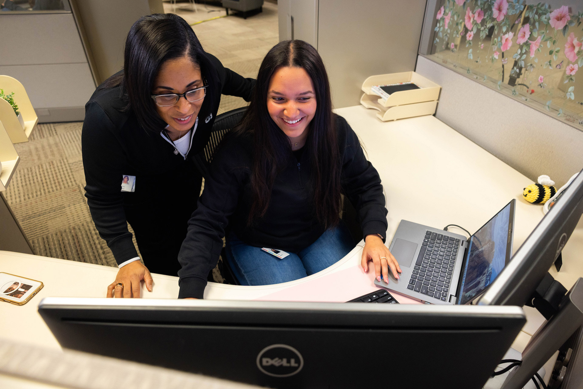 Two people in a cubicle looking at a computer