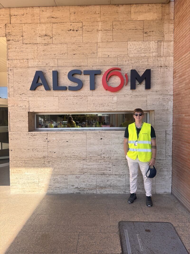 A person poses for a picture outside of Alstom