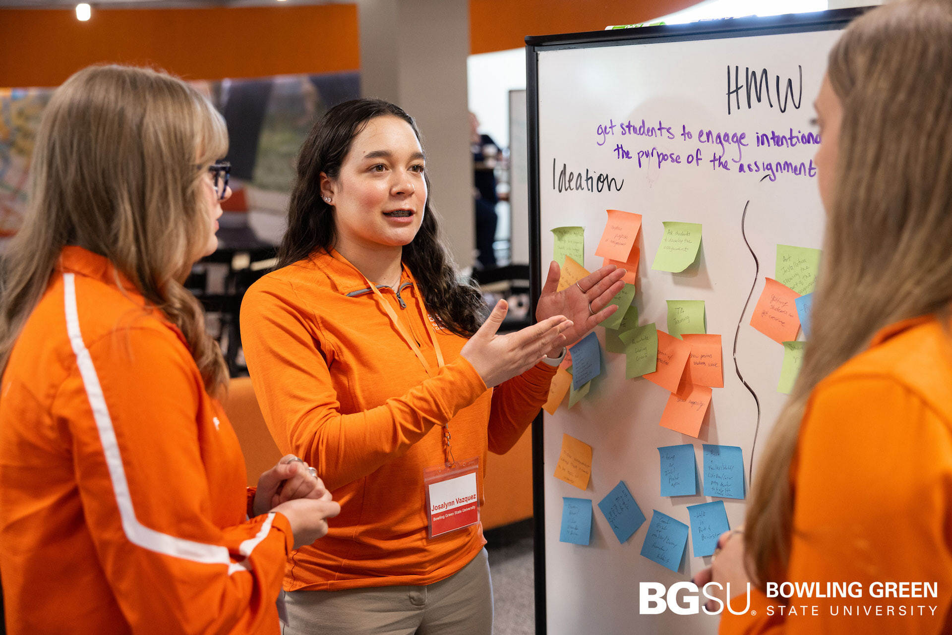 A student speaks near a whiteboard filled with Post-It notes.