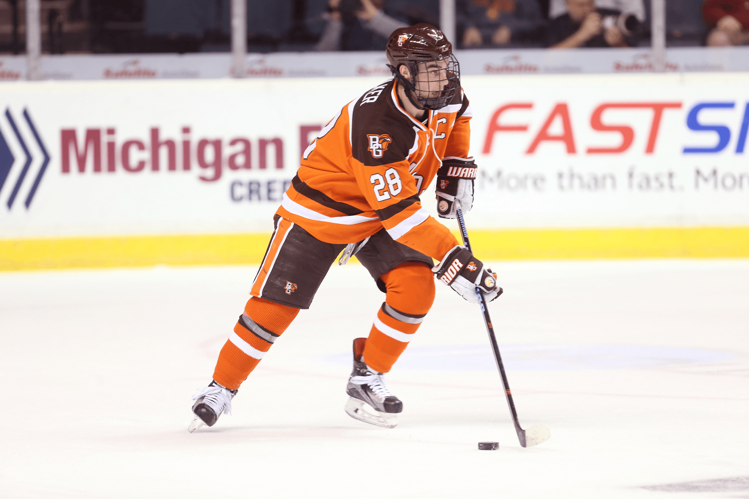 A hockey player skates with the puck.