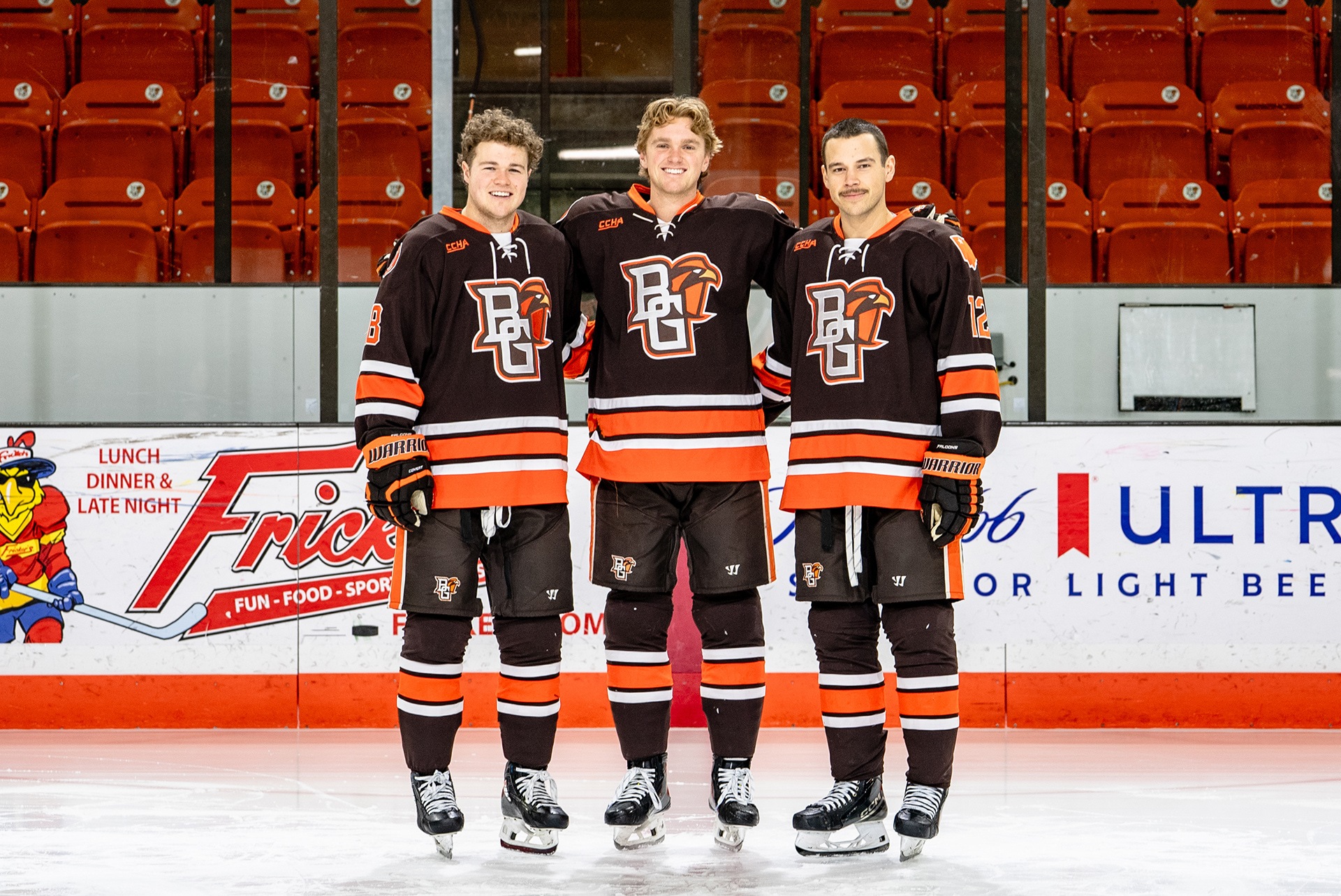 Three hockey players stand on the ice.