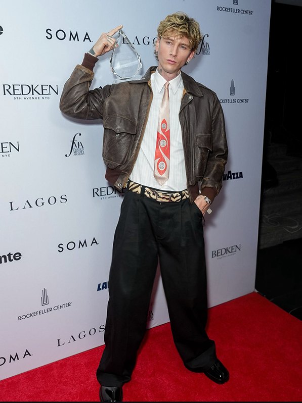 A person poses for a picture while holding an award on his shoulder