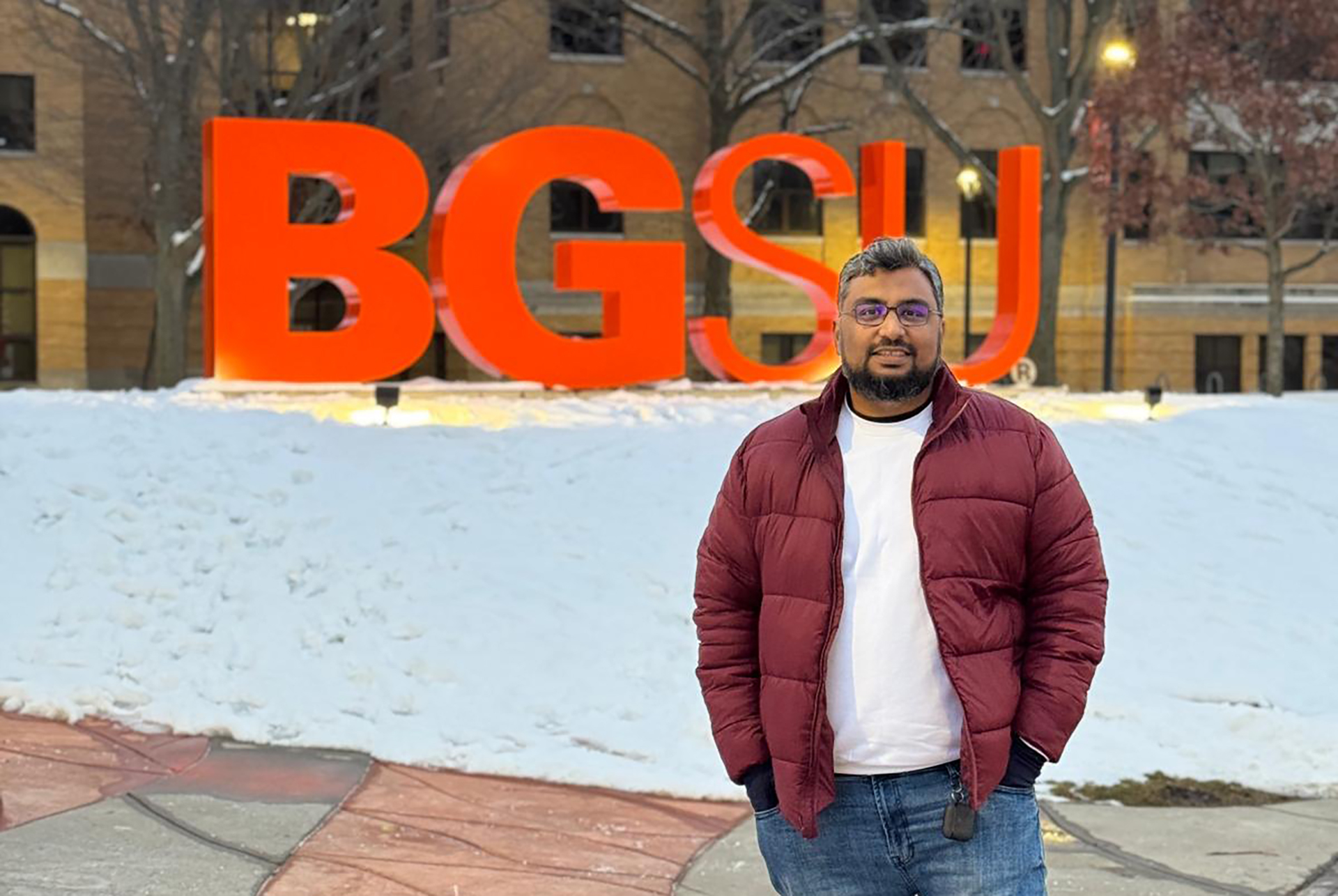 A person stands in front of the "BGSU" letters at Bowling Green State University