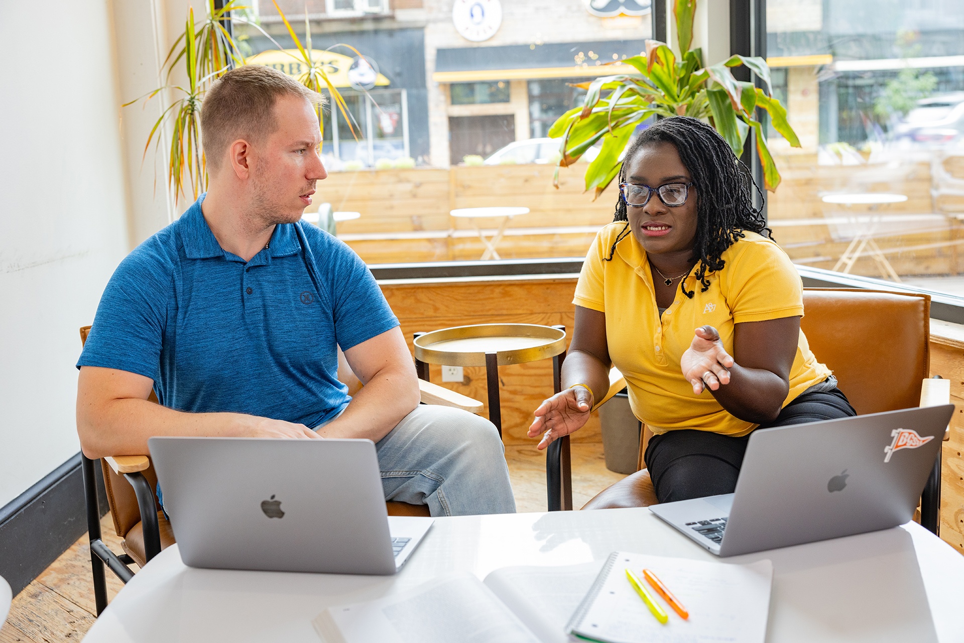 Two BGSU students work on laptops in a coffee shop.