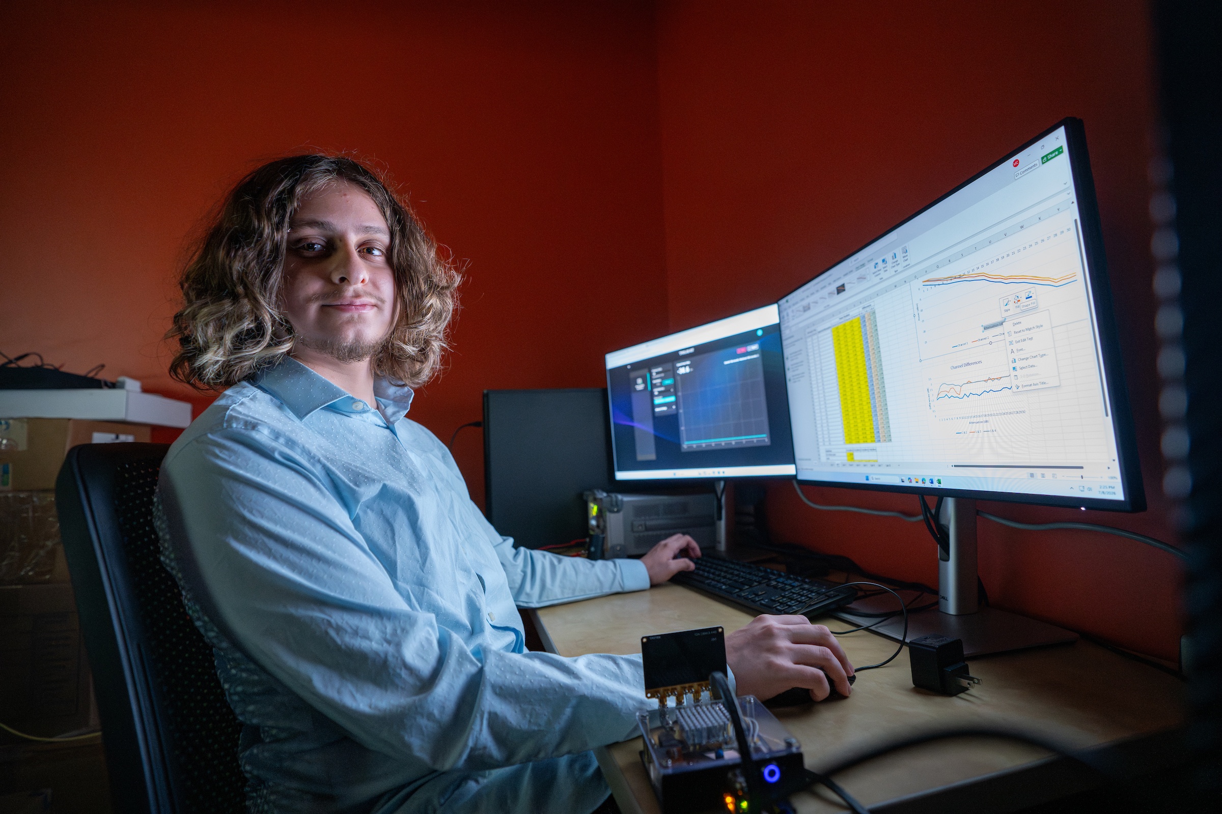 A person poses for a picture while working on a computer