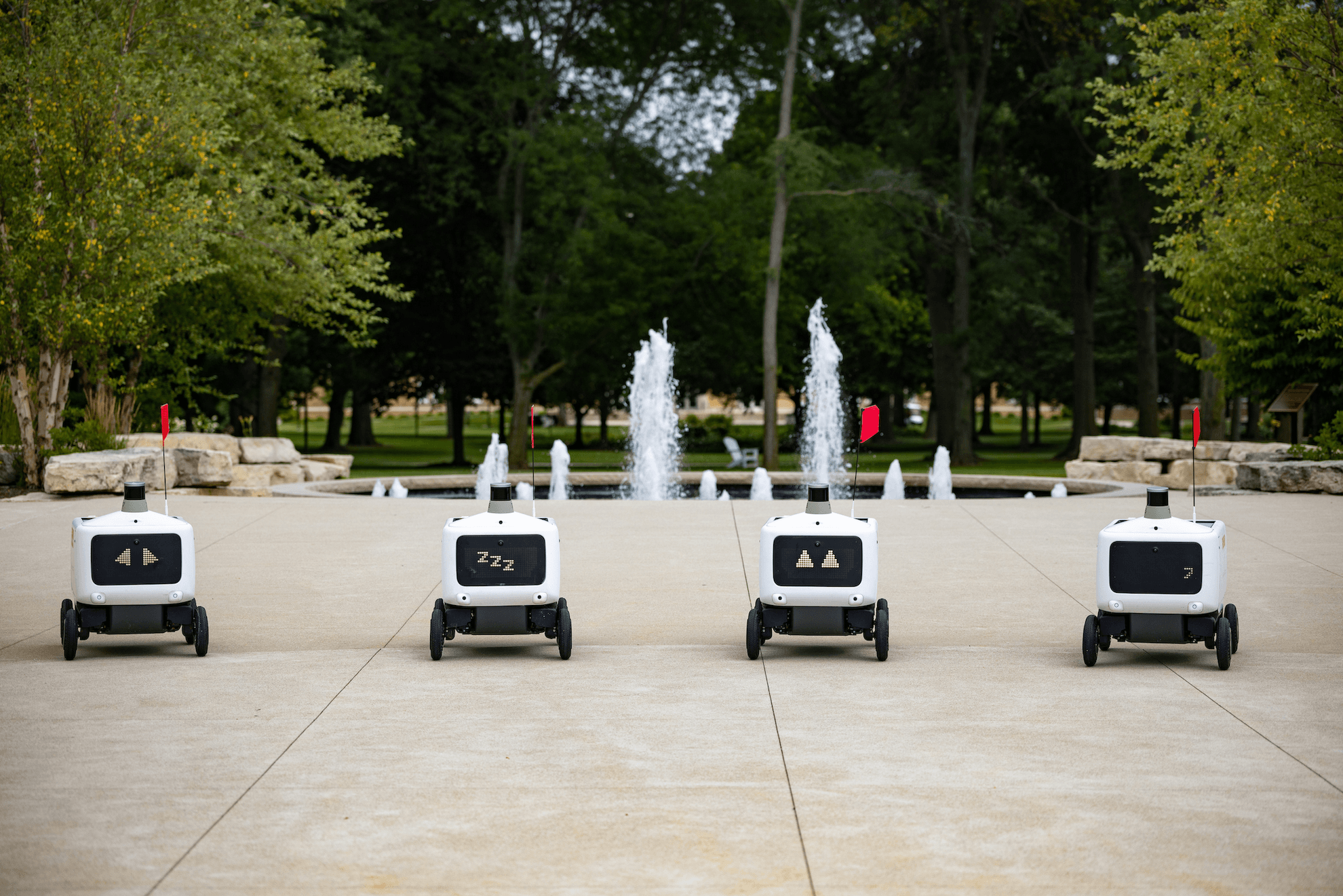 Delivery robots in front a fountain.