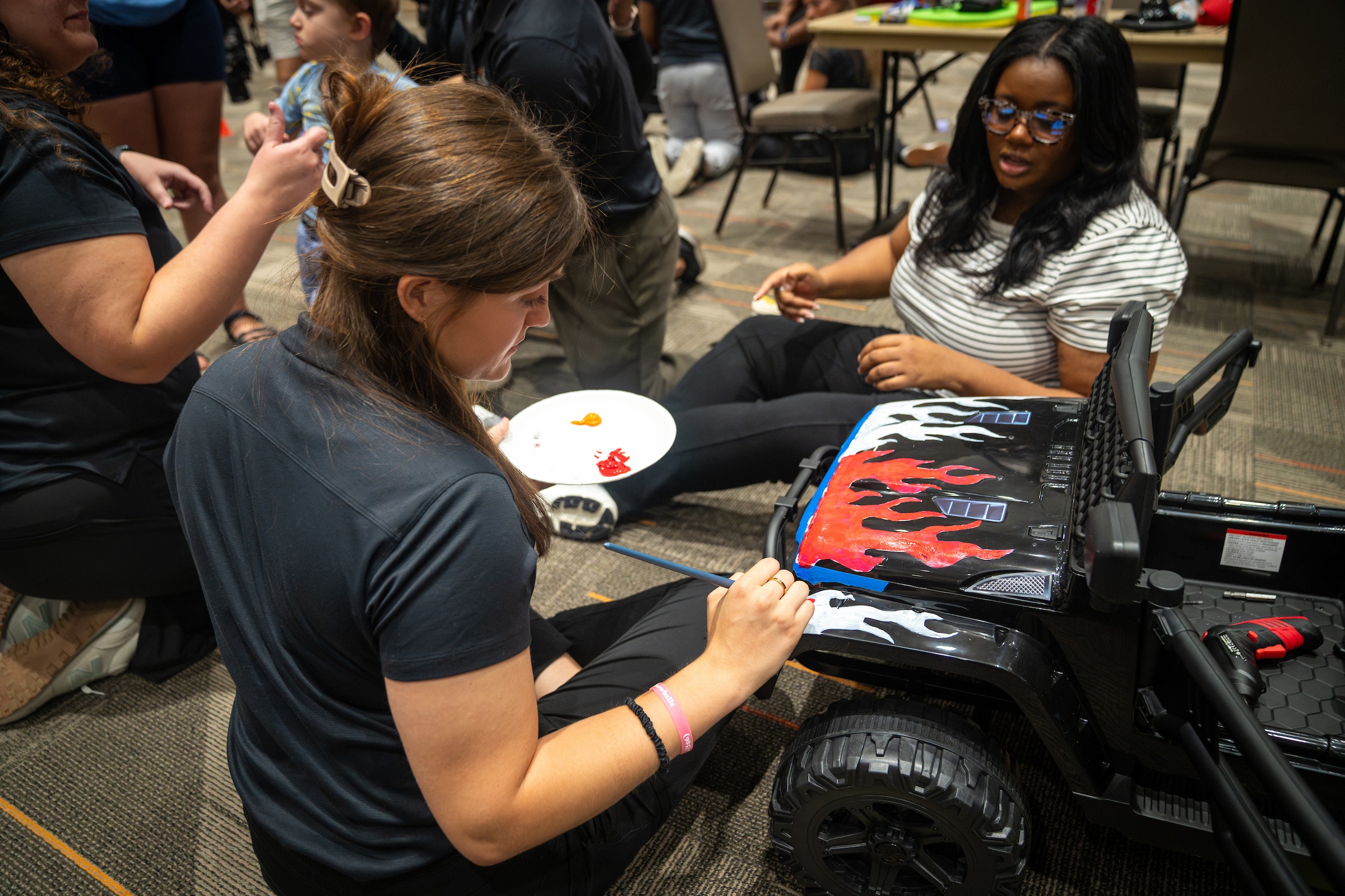 A person paints flames on a toy car.