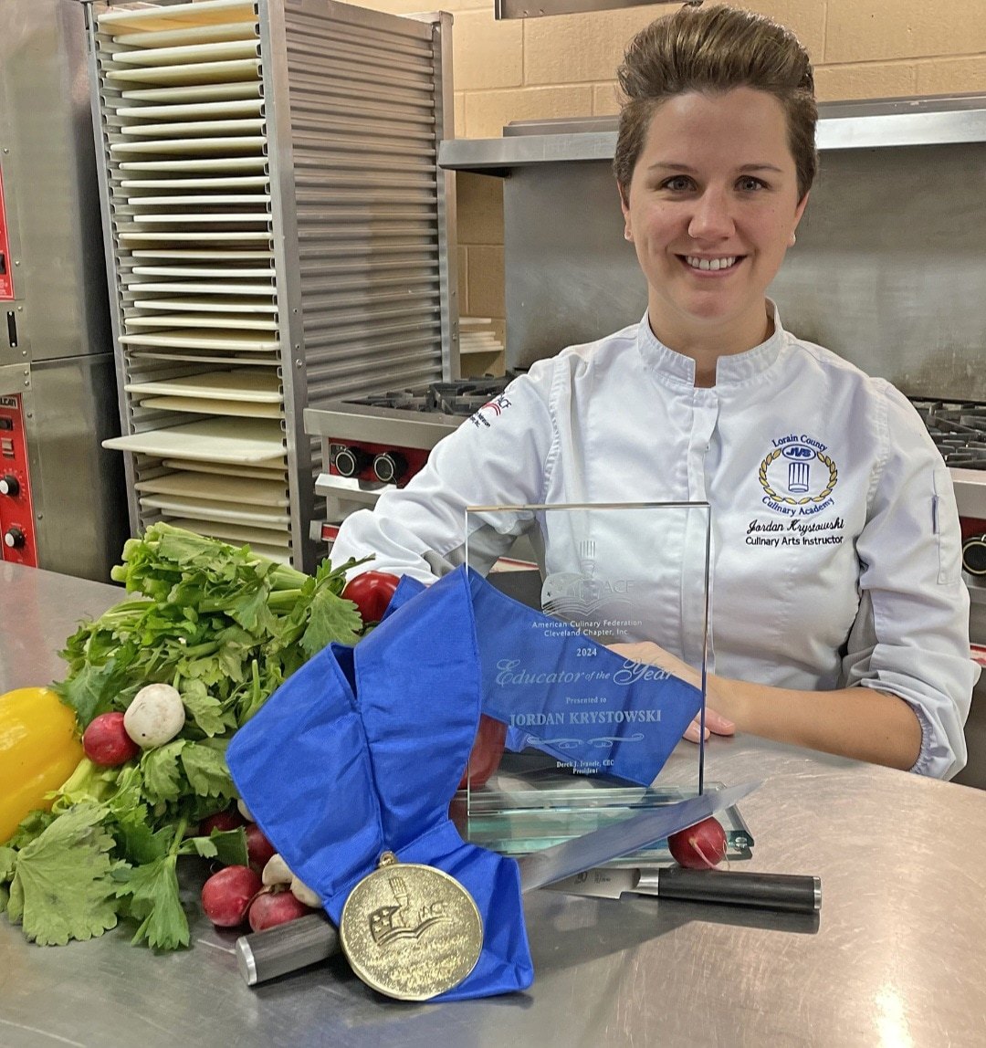 A chef poses for a photo with an award and food