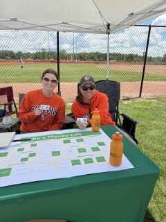 Two people sit behind a table.