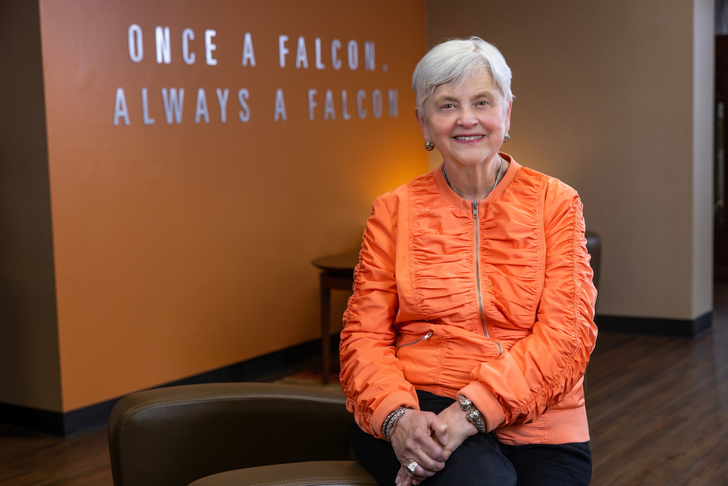 BGSU President Emeritus Mary Ellen Mazey in front a sign that reads "Once a Falcon, Always a Falcon"