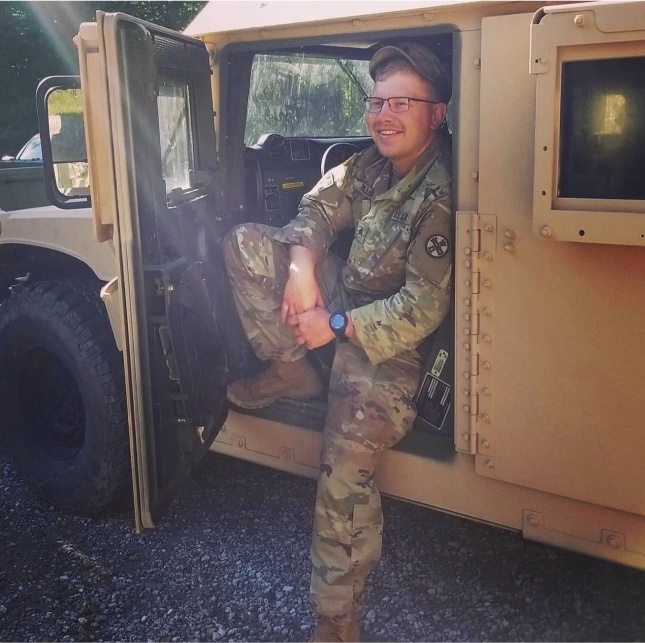 A military member sits in a parked vehicle