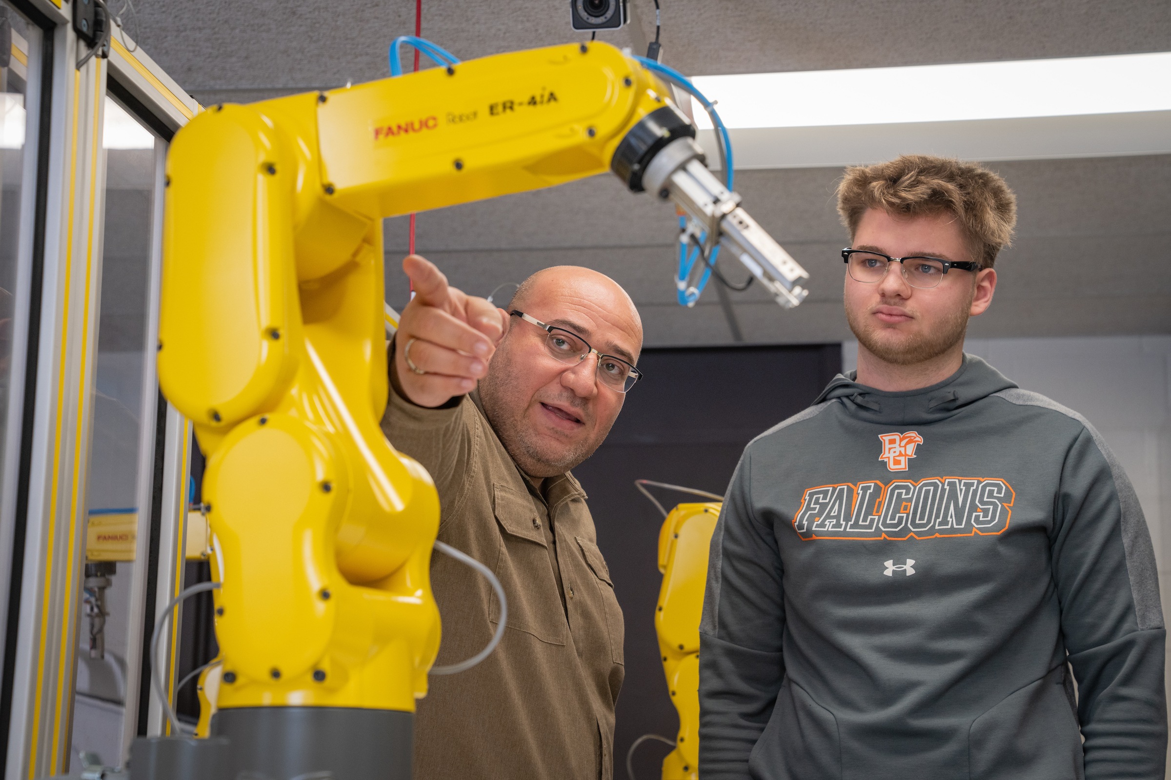 A professors discusses engineering equipment with a student.