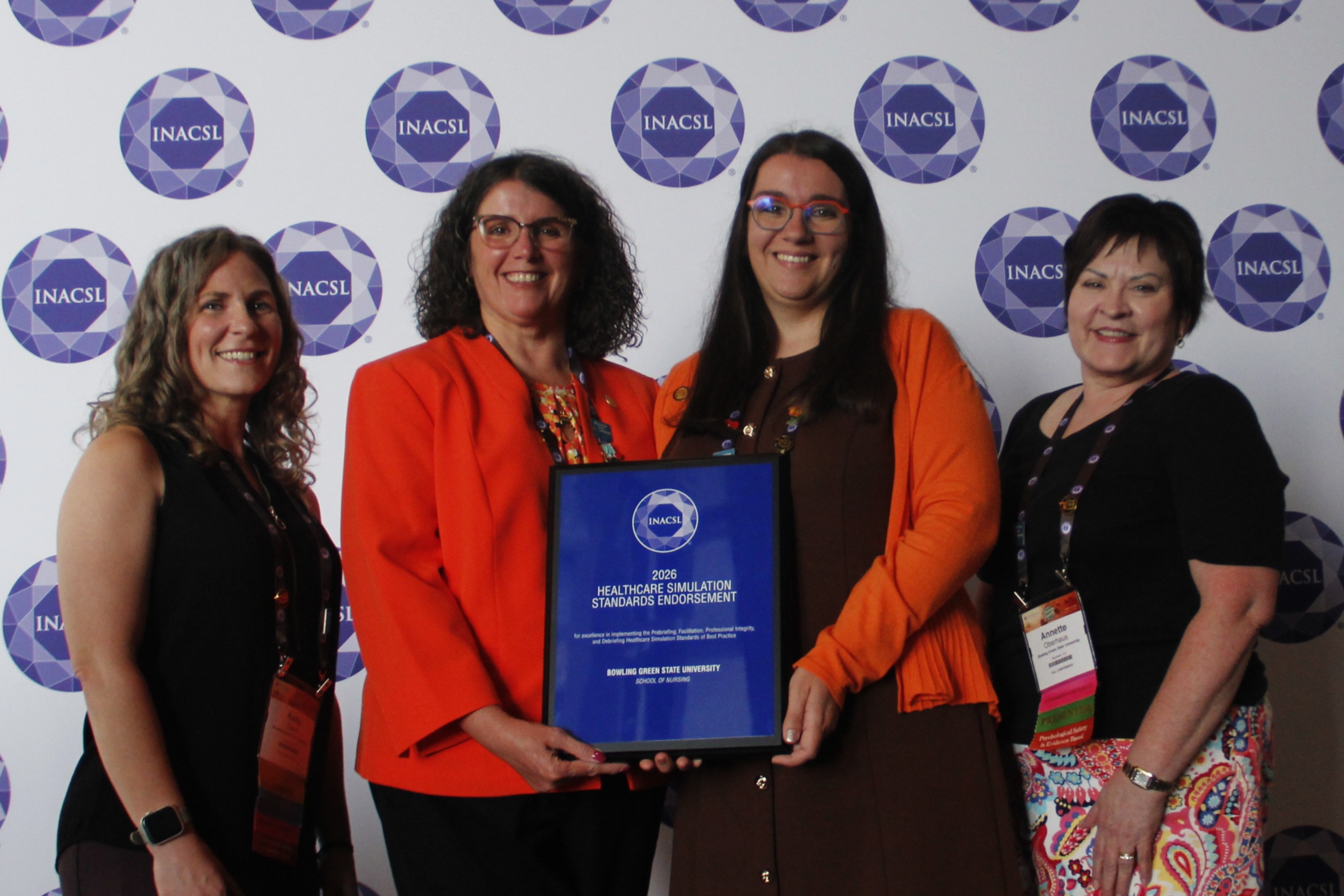 Four people pose with a plaque