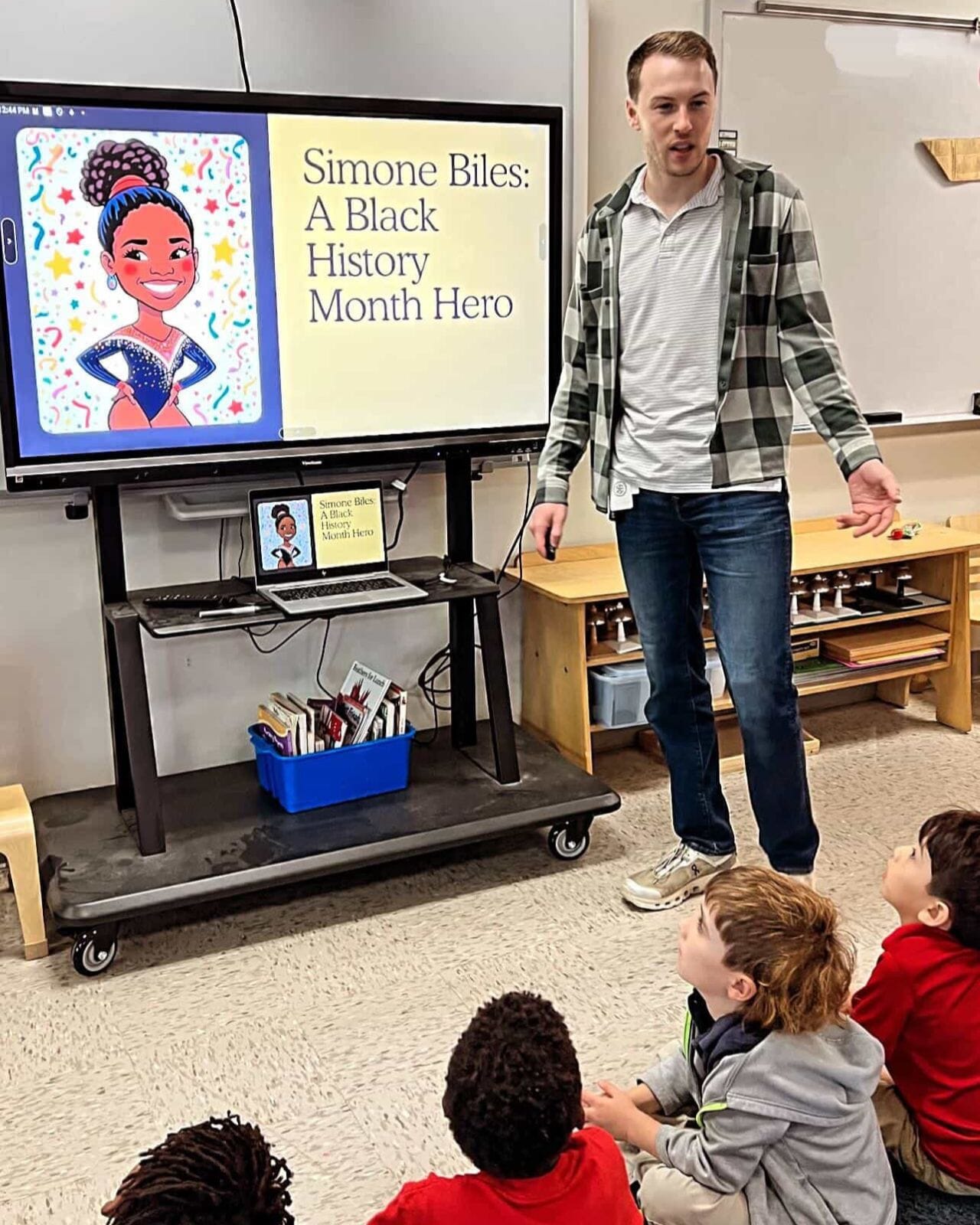 A teacher presents near a video board.