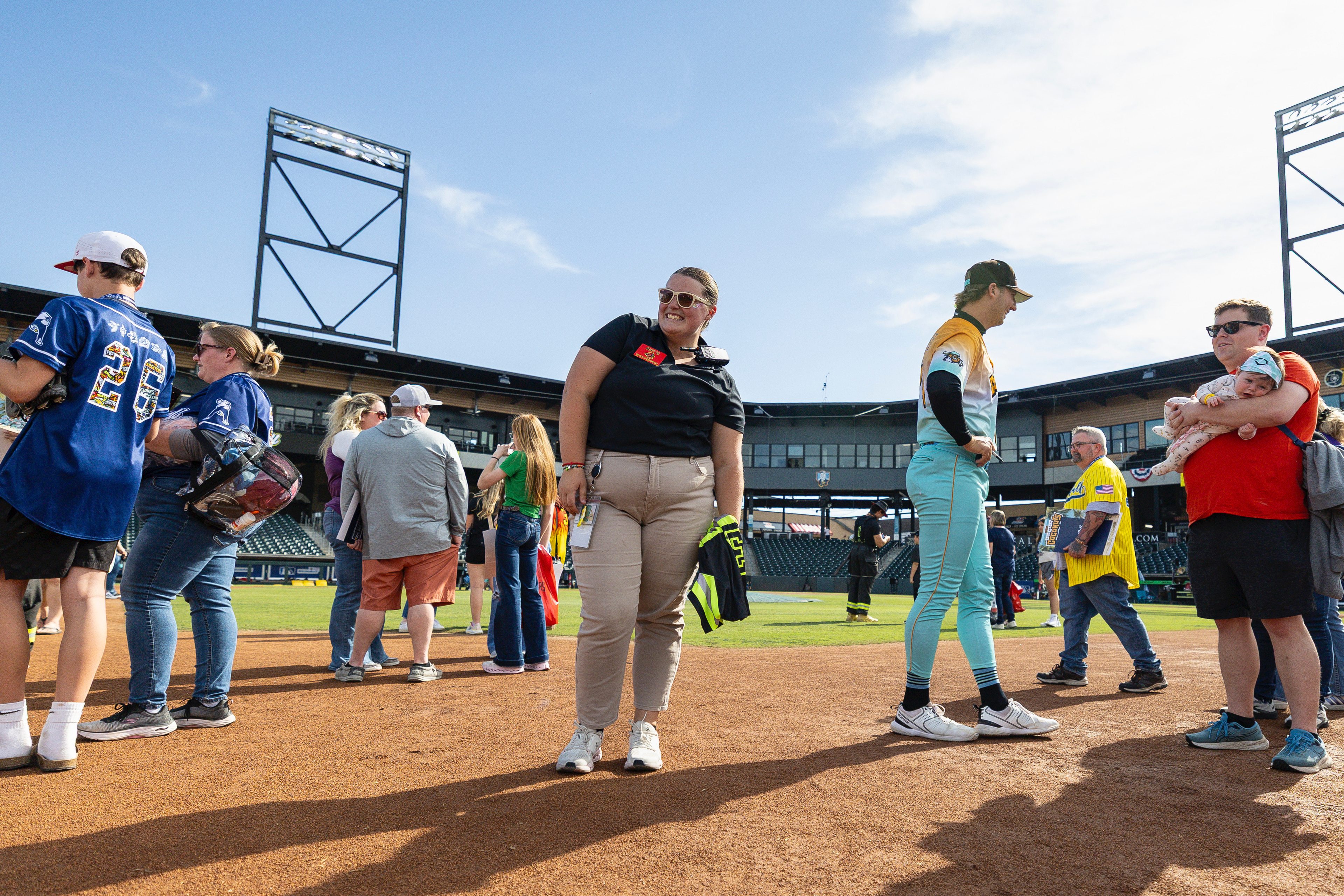 A person smiles on the infield of a baseball stadium.