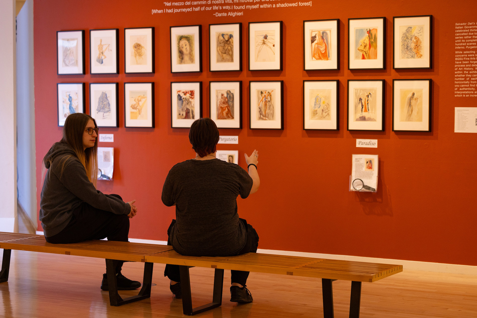 Two people sit on a bench in the art exhibition.