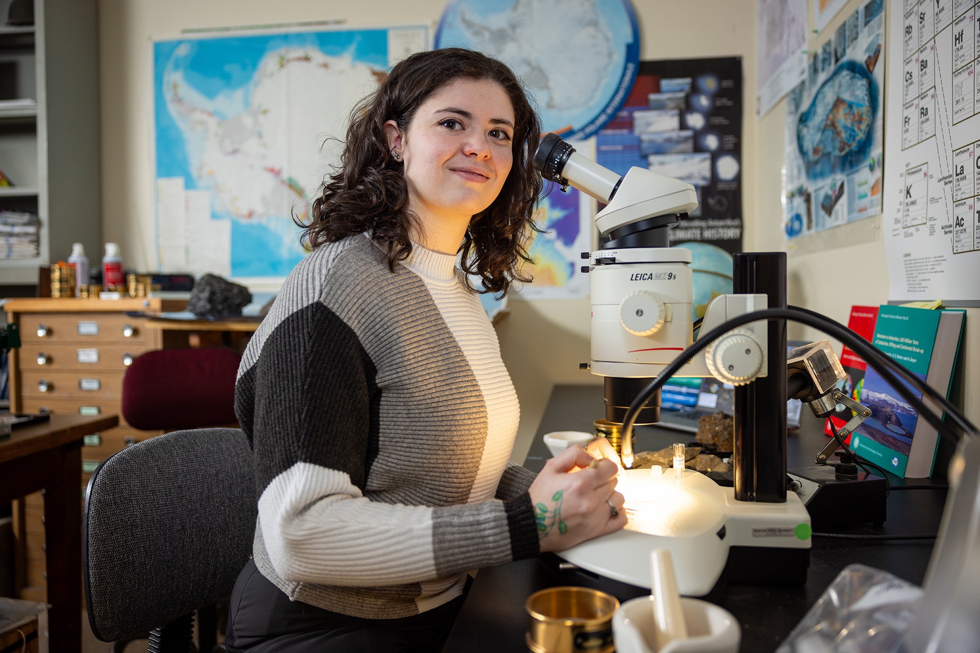 A person poses at a microscope.