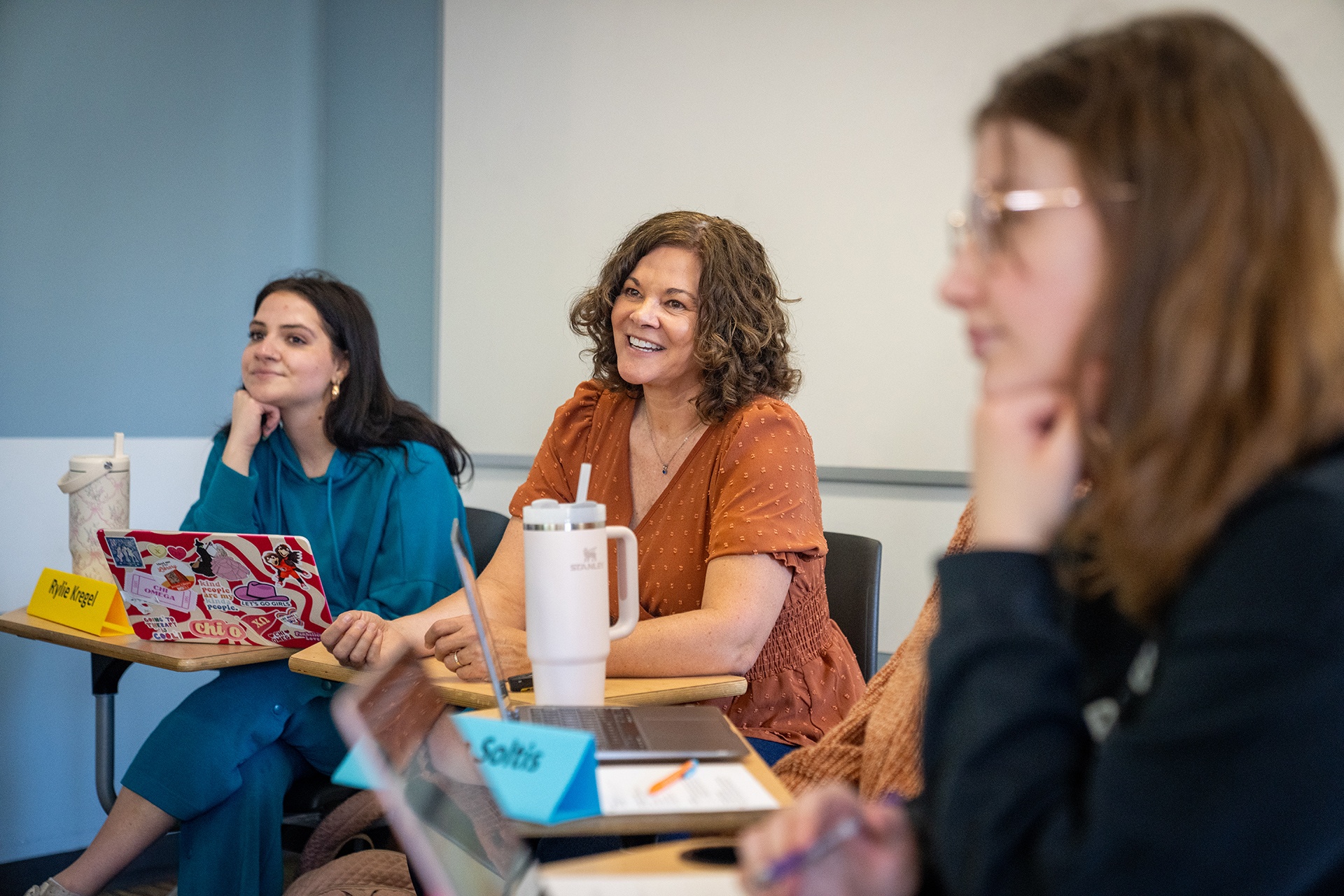A teacher smiles as she interacts with students.