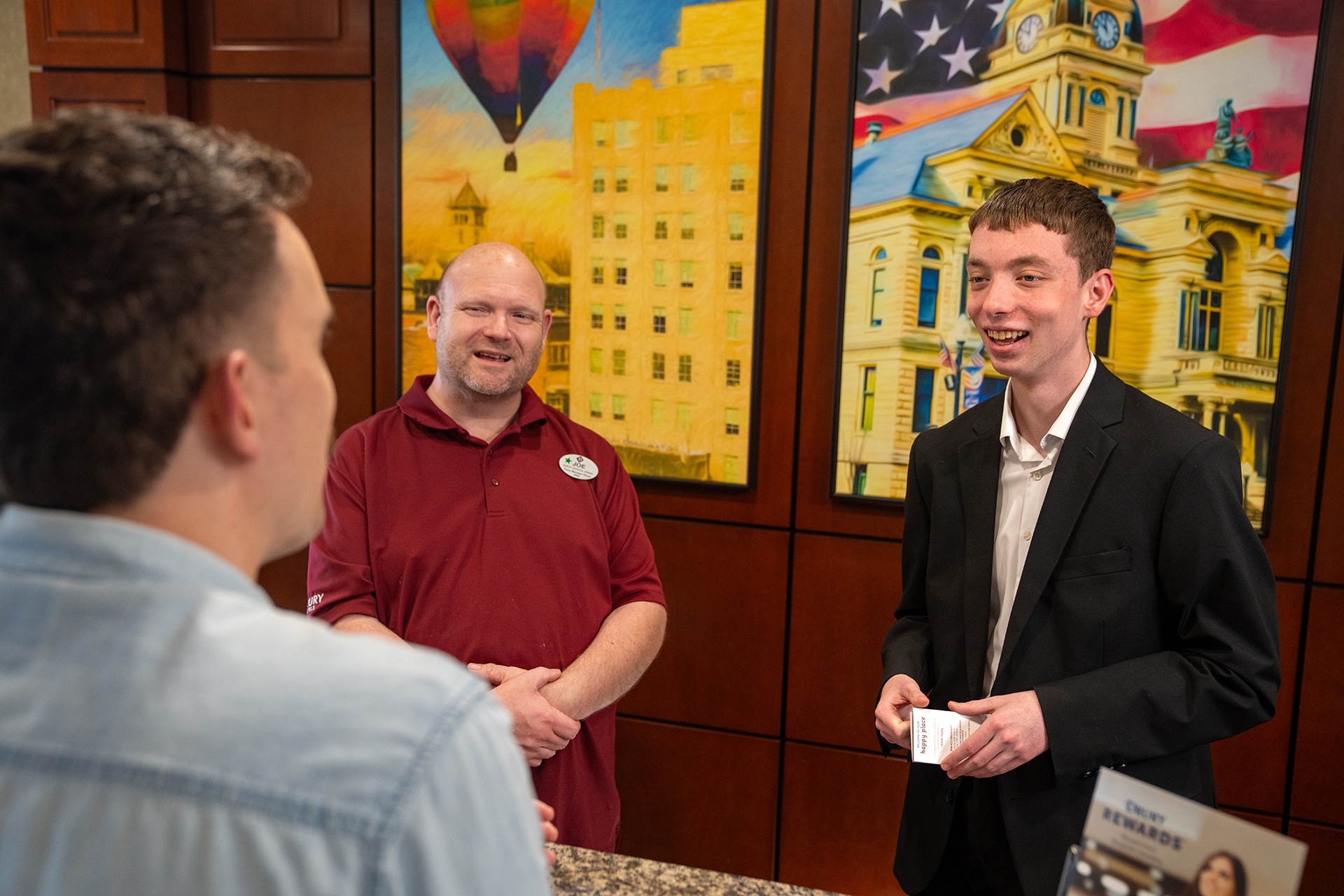 Two employees help a customer at a service desk