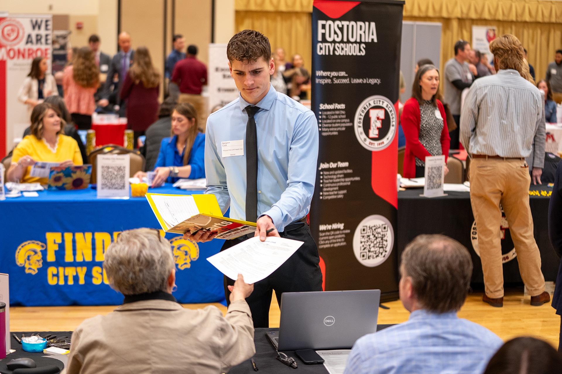 A student hands his resume to a recruiter at a career fair