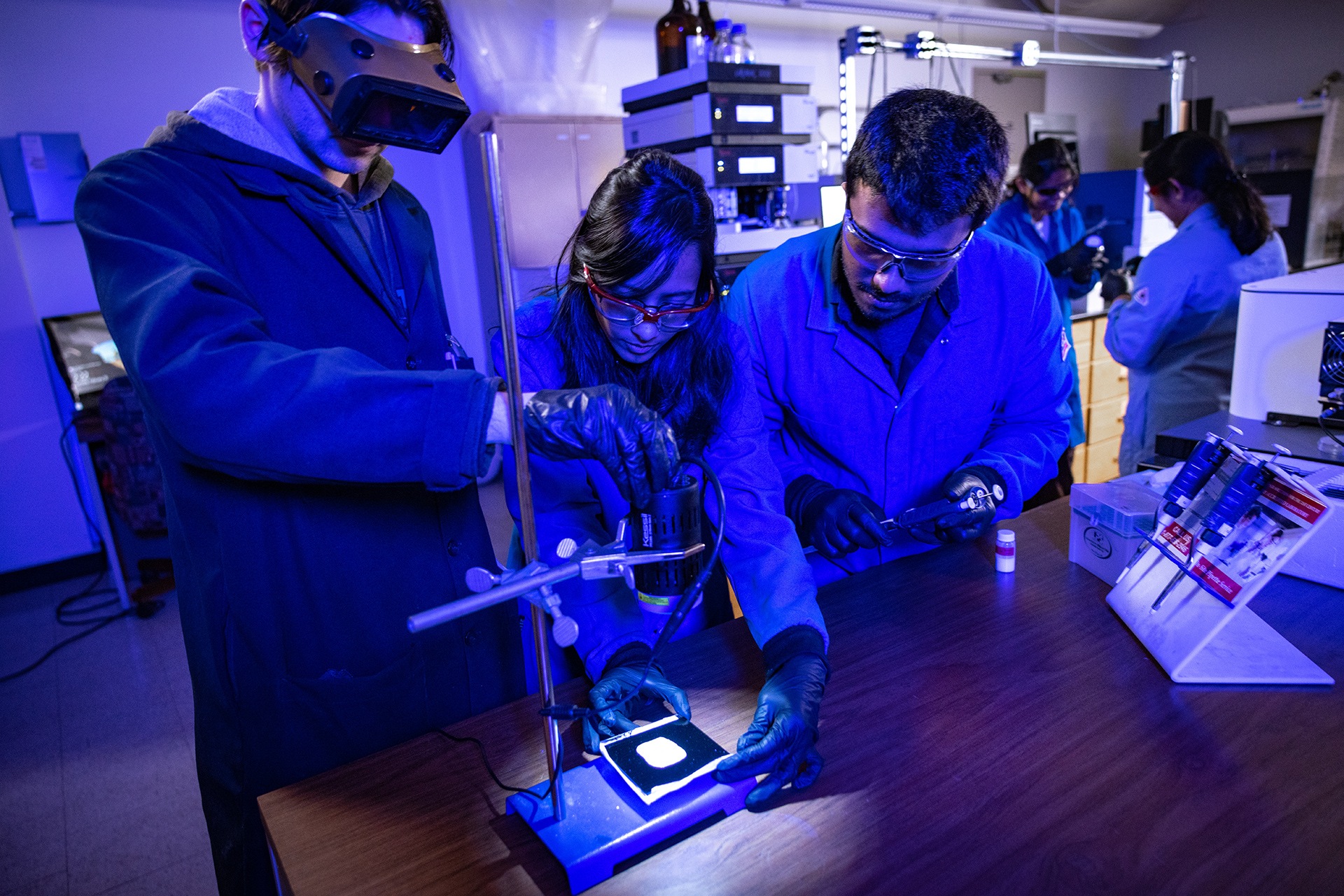 Students look at a solar panel under UV lights.