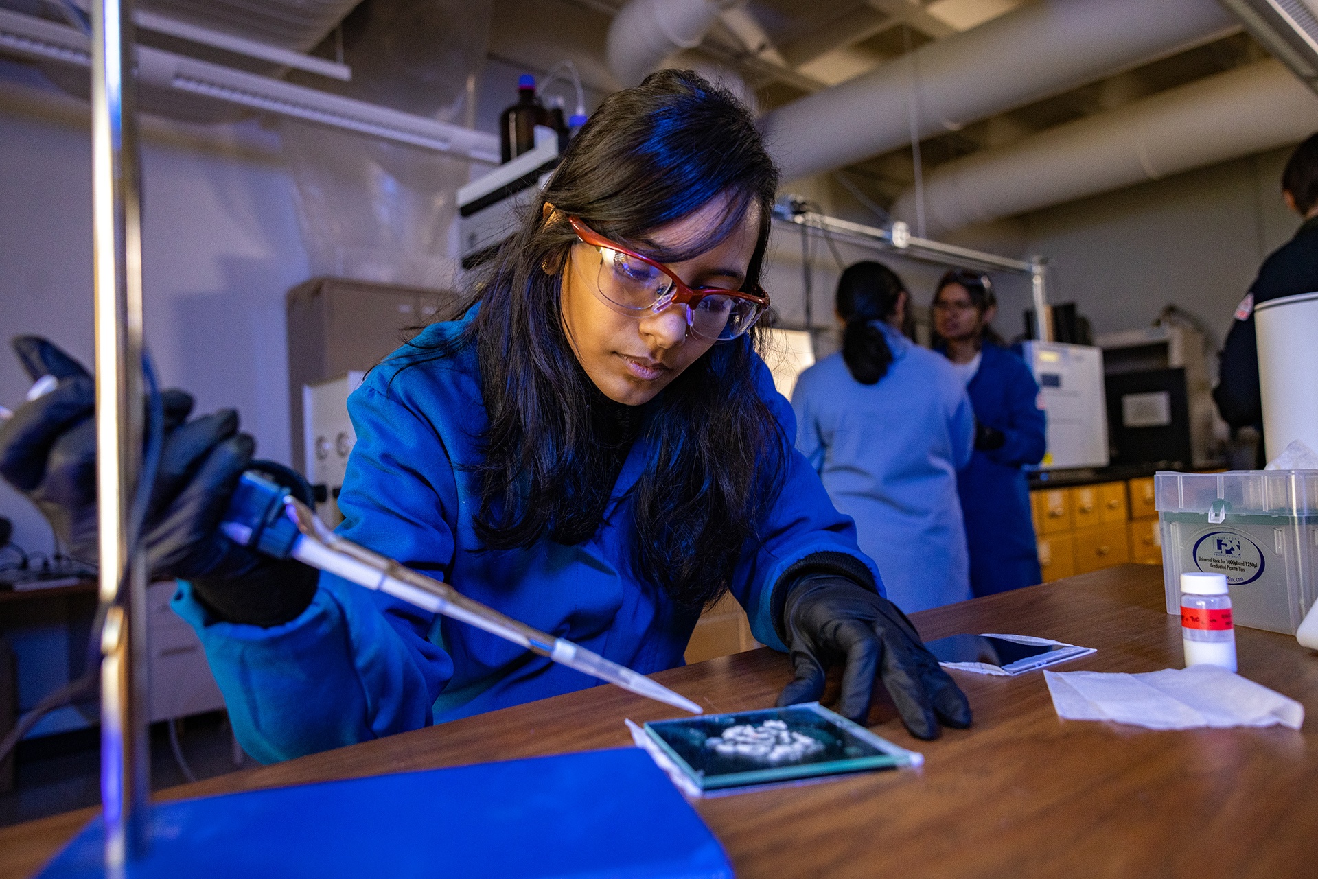 A student wearing safety glasses works in a lab