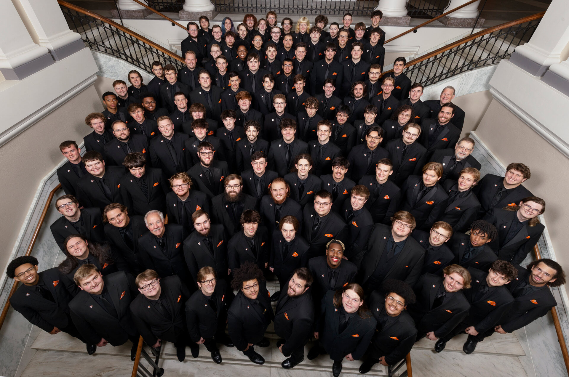 A choir poses for a photo on a flight of stairs.