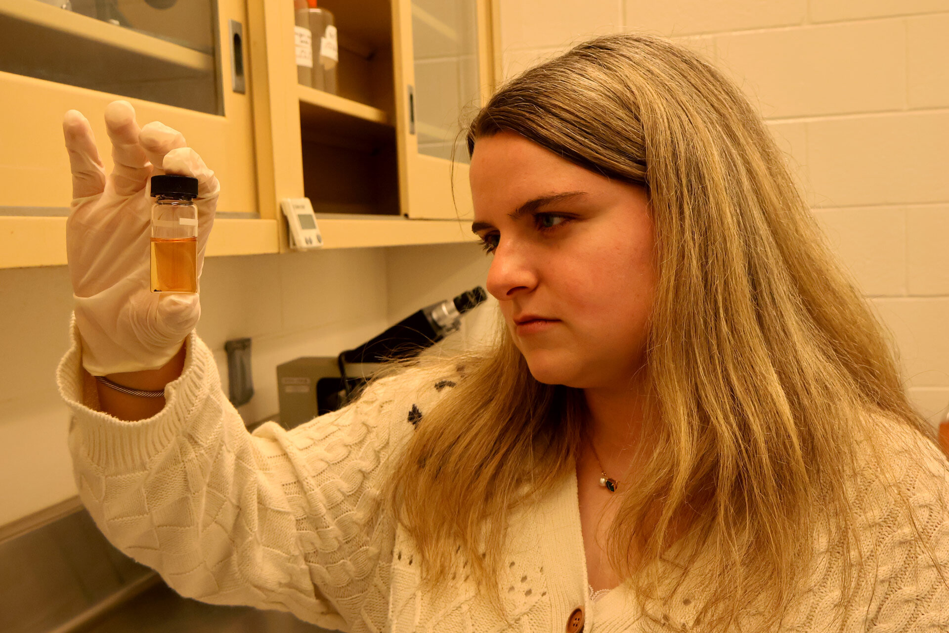 A student holds a water sample during lab analysis.