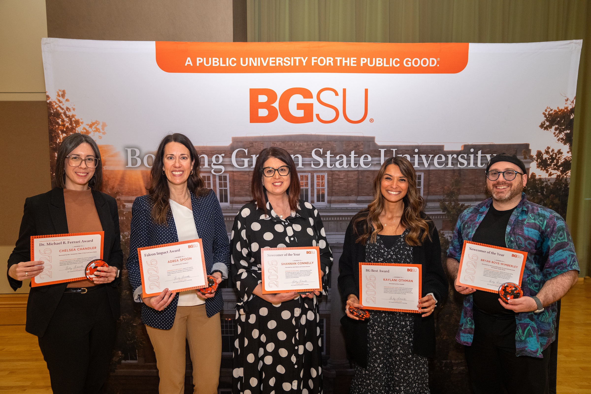 A group of people poses while holding award certificates