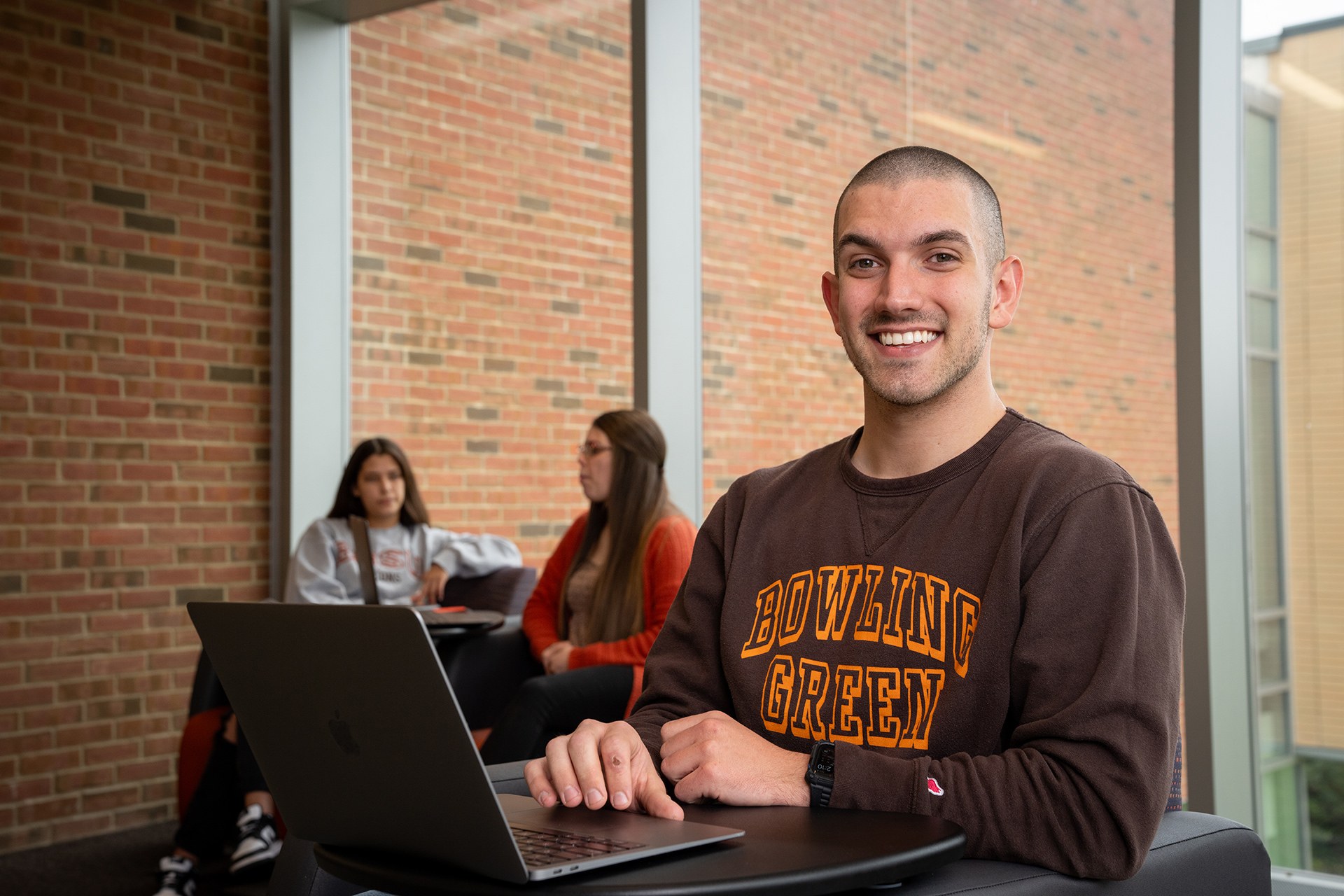 A person smiles with a laptop in front of him
