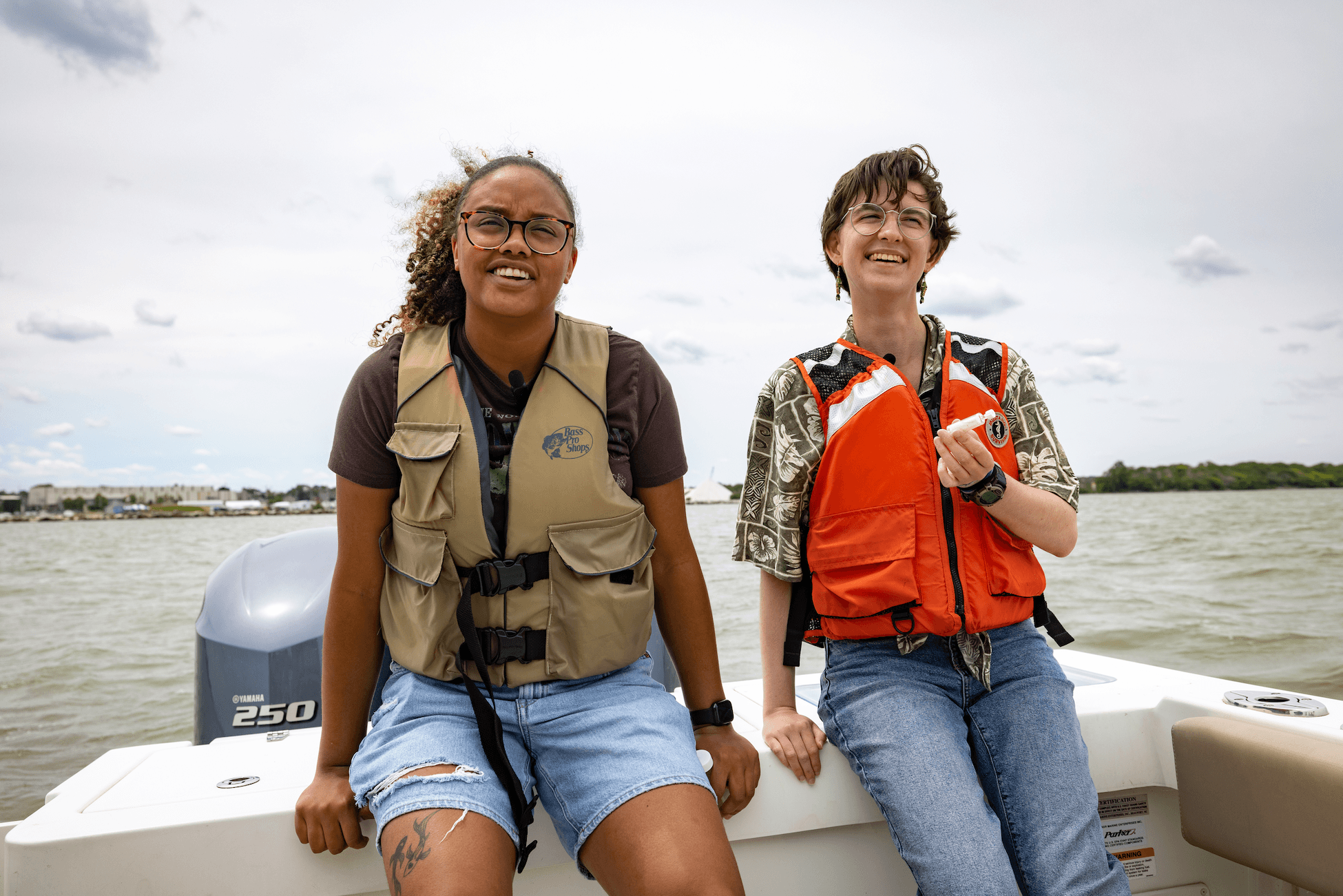 Two students smile aboard a boat.