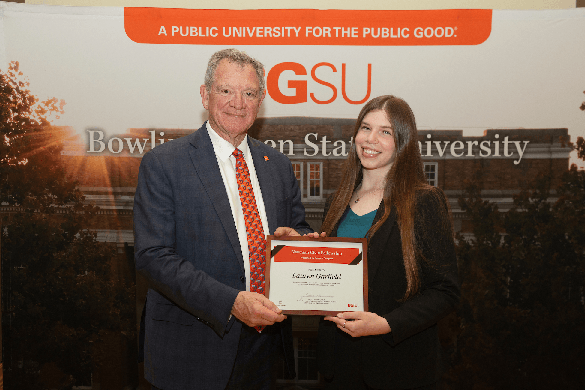 Two people pose for a photo with a certificate.