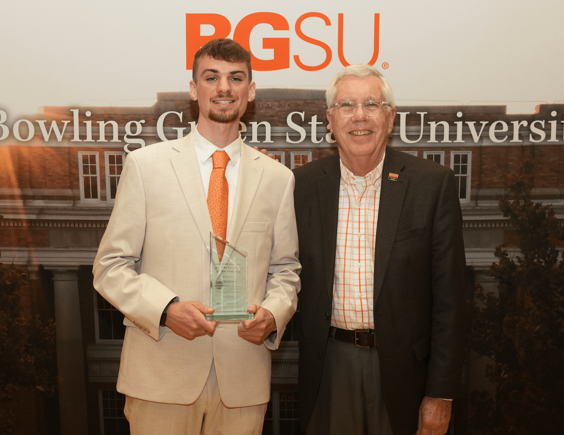 Two people pose for a photo with an award.