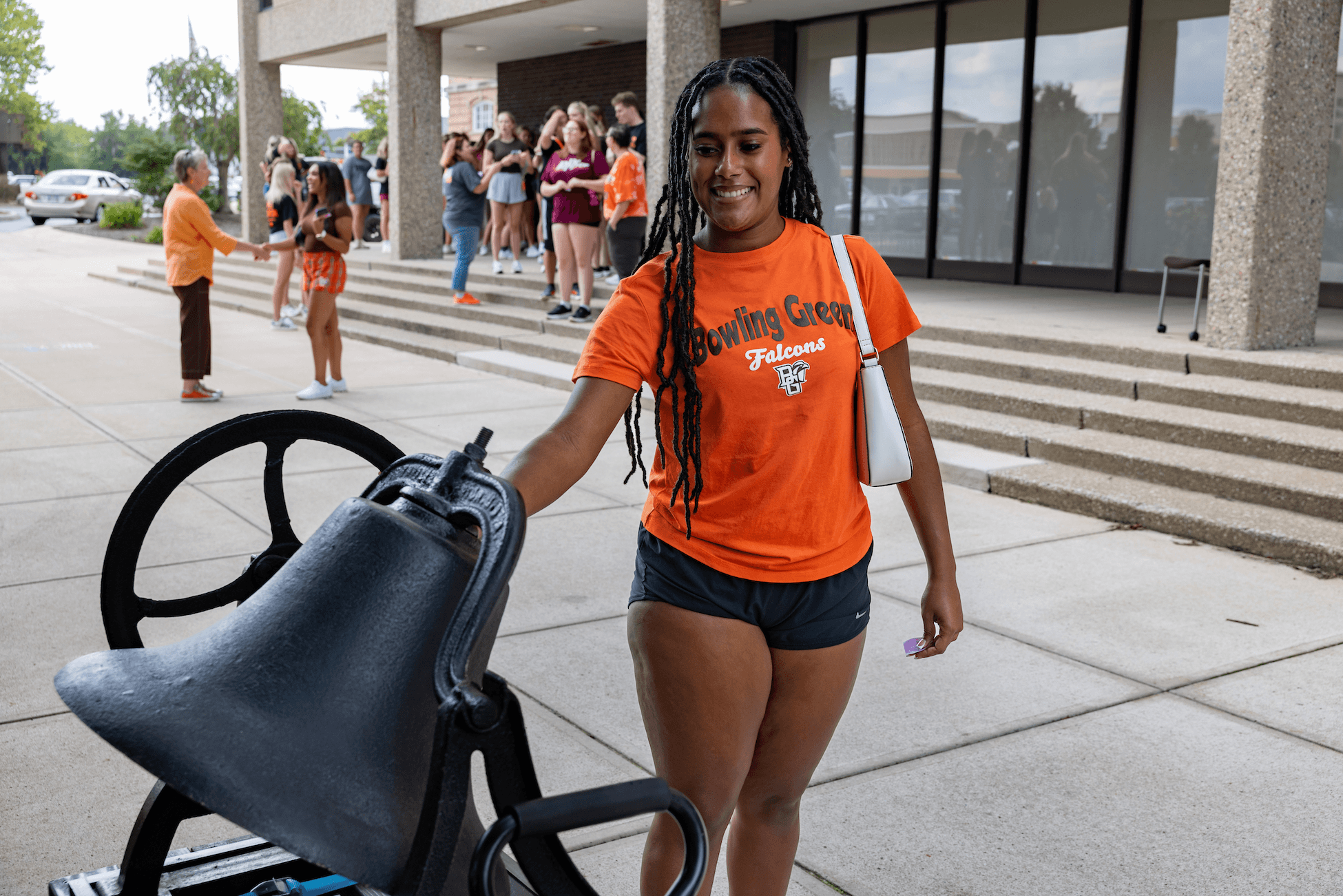 A girl in a BGSU shirt rings a bell.